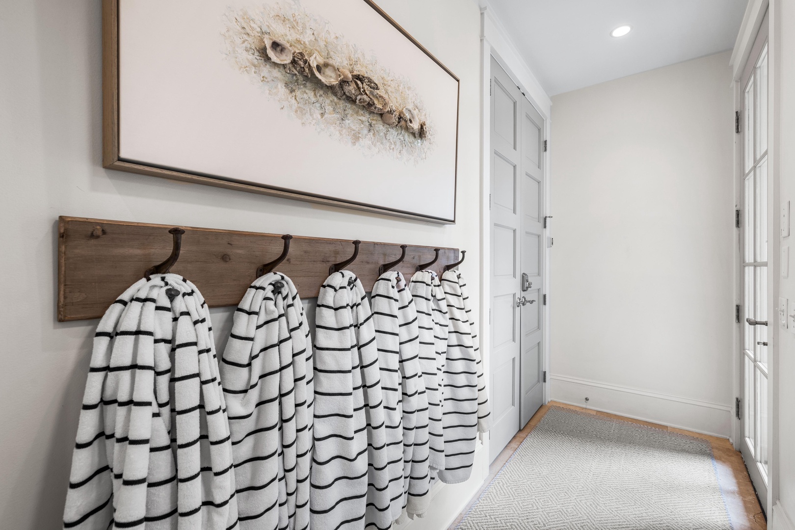 Your organized entryway features stylish striped robes hanging ready for your beach day and cozy towels waiting to wrap you up.