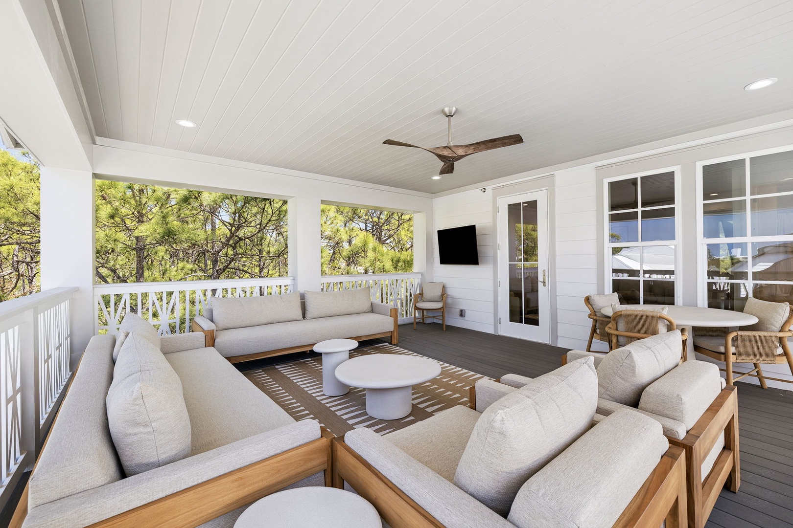 Relax on your private covered terrace with comfortable lounge seating, ceiling fan, and peaceful garden views through elegant white railings.