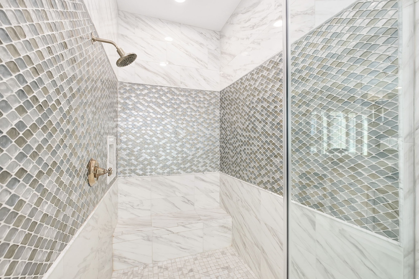 Step into your luxurious marble shower with stunning mosaic tile walls and elegant fixtures for the ultimate spa experience.