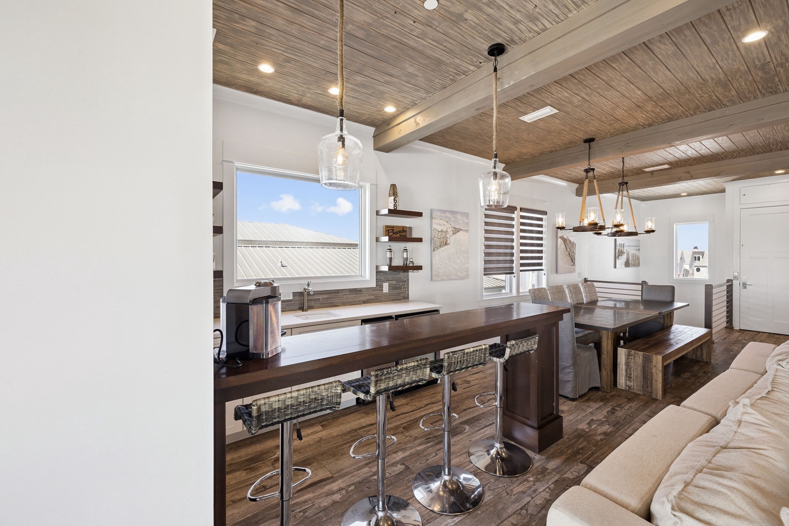Gather around this stunning open kitchen and dining space, where rustic wood beams meet modern style for unforgettable meals together.