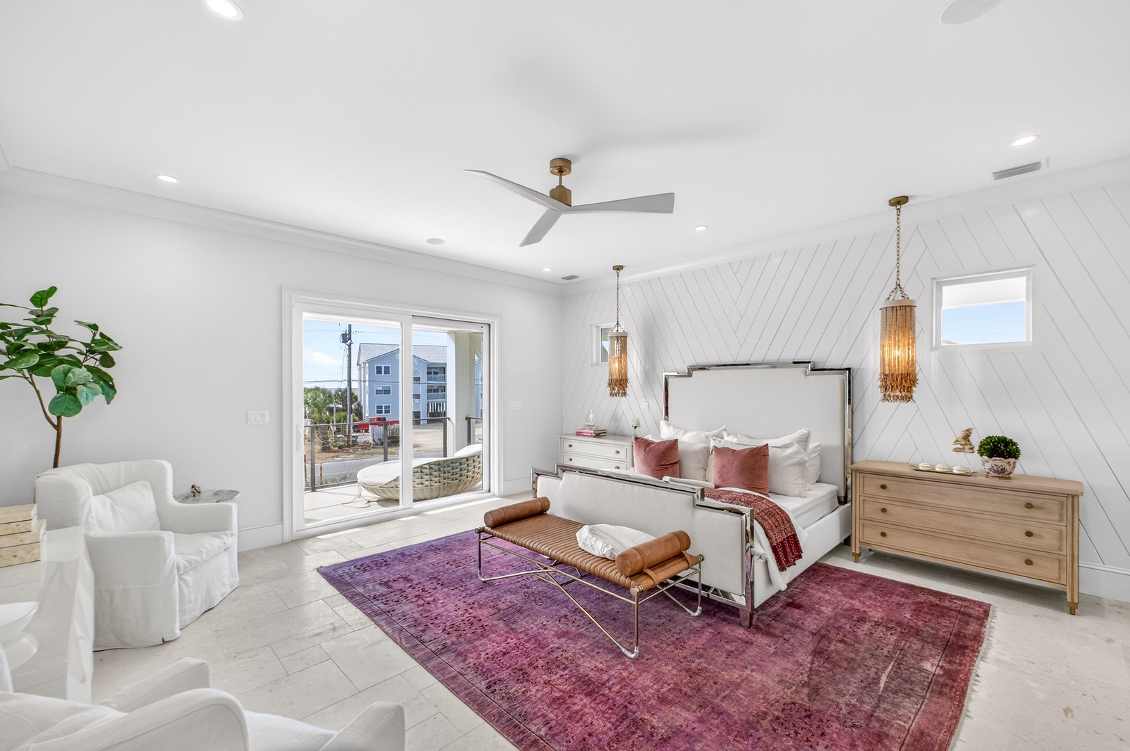 Unwind in your elegant bedroom sanctuary with cozy seating, striking purple accents, and doors opening to your private outdoor space.