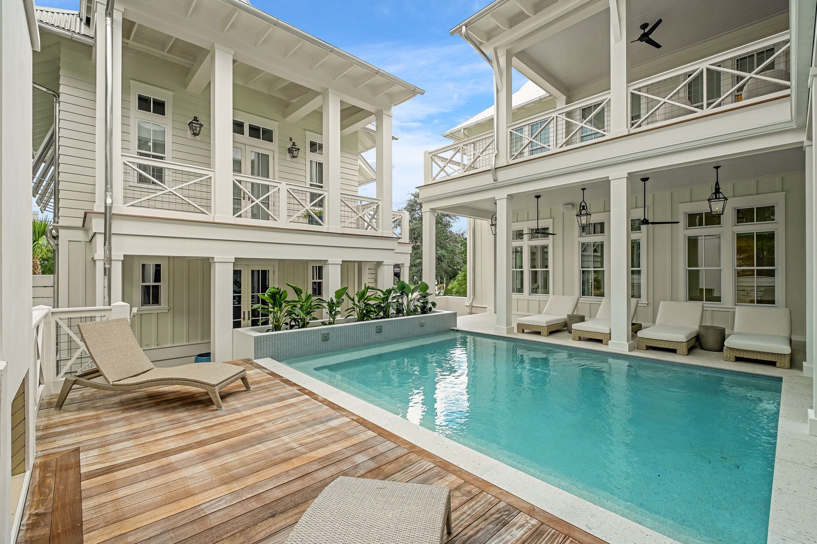Elegant private courtyard with a sparkling pool framed by classic white architecture and covered porches—your personal retreat for sunny afternoons and quiet evenings.