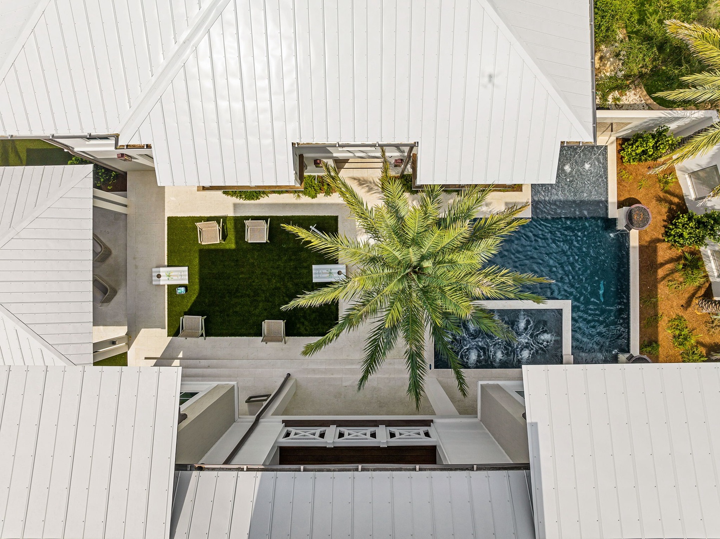 This modern tropical retreat features a sparkling pool, lush lawn, and comfortable lounge seating—all framed by swaying palms and surrounded by privacy.