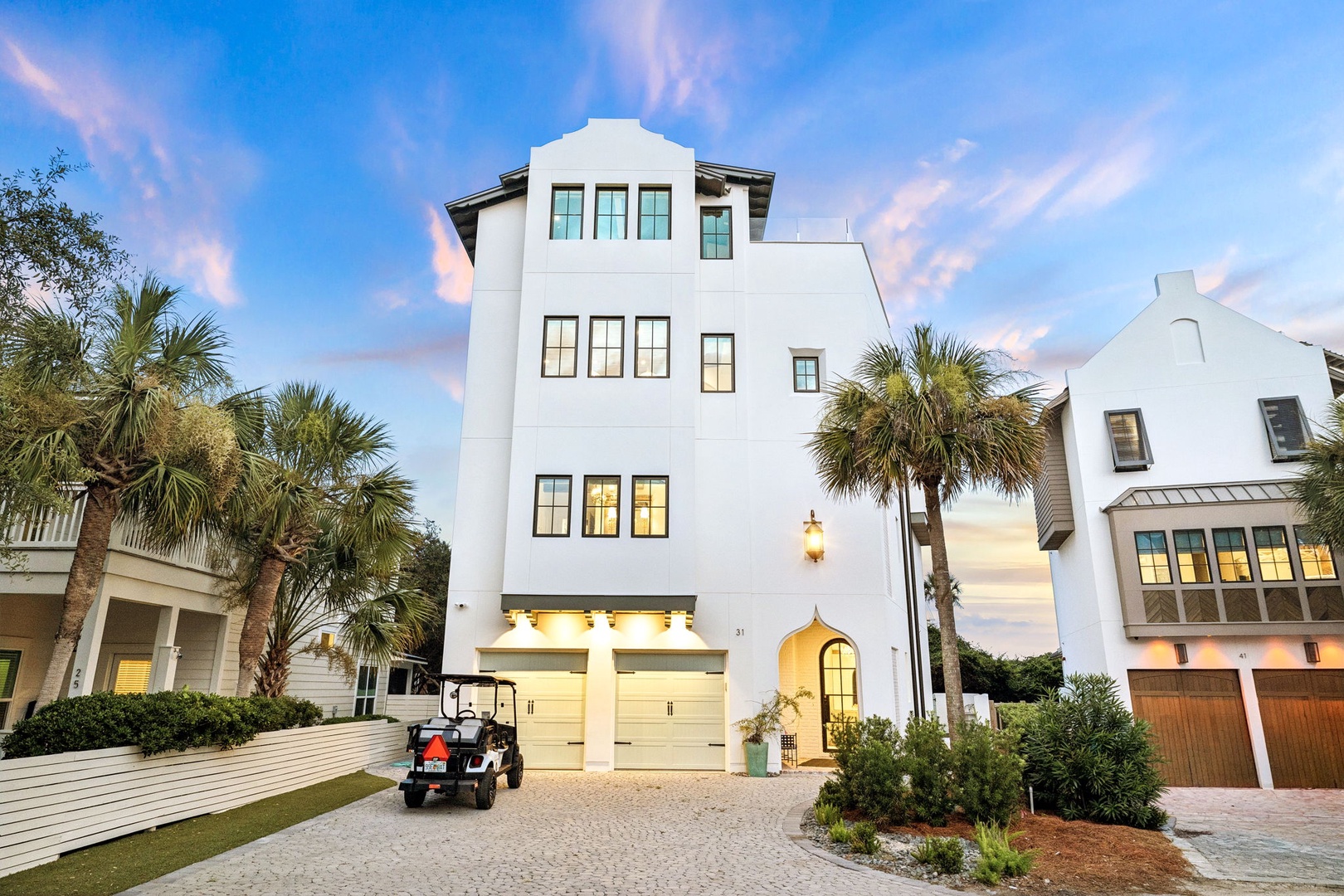 This stunning coastal property features Mediterranean-inspired architecture with palm trees and a convenient golf cart, perfect for exploring the neighborhood during your stay.