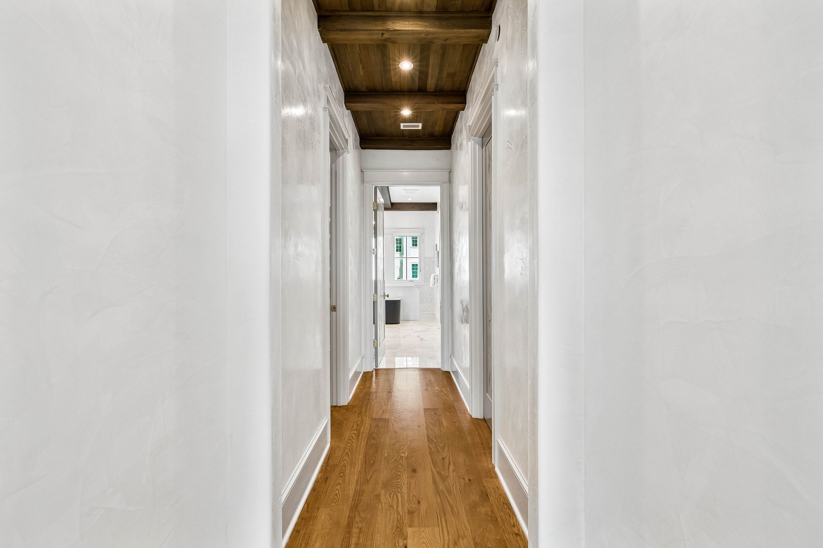 Walk through this bright hallway with gleaming hardwood floors and rustic wood-beam ceilings that add warmth and character to your home away from home.