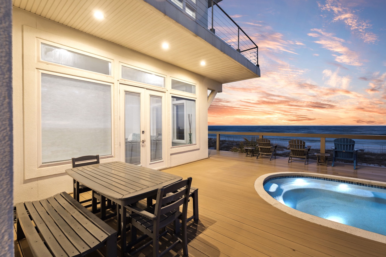 Stunning oceanfront deck with private hot tub where you'll unwind under painted sunset skies, perfect for memorable evenings by the sea.