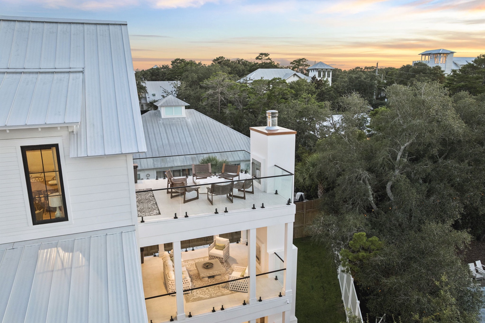 Modern coastal retreat nestled among lush trees, with spacious private terraces for relaxing and watching the sunset paint the sky in warm colors.