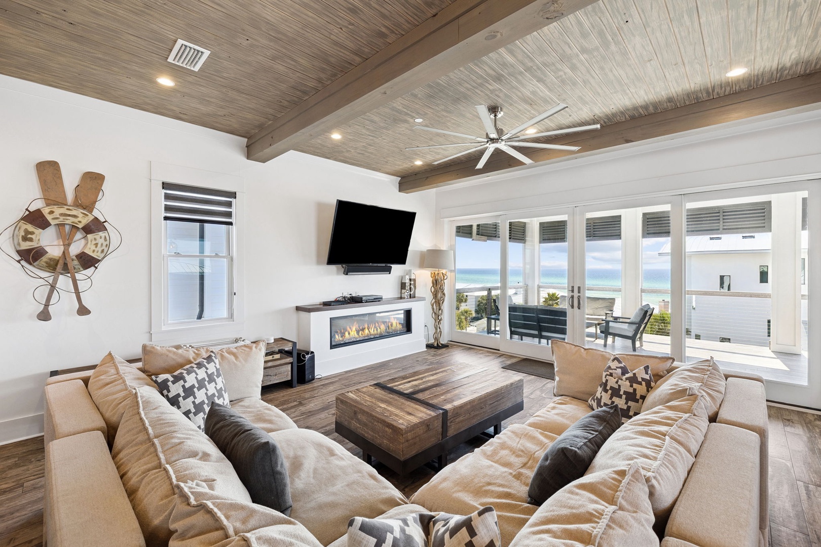 Sink into plush coastal comfort while ocean views frame your days through floor-to-ceiling windows in this stylish living space.