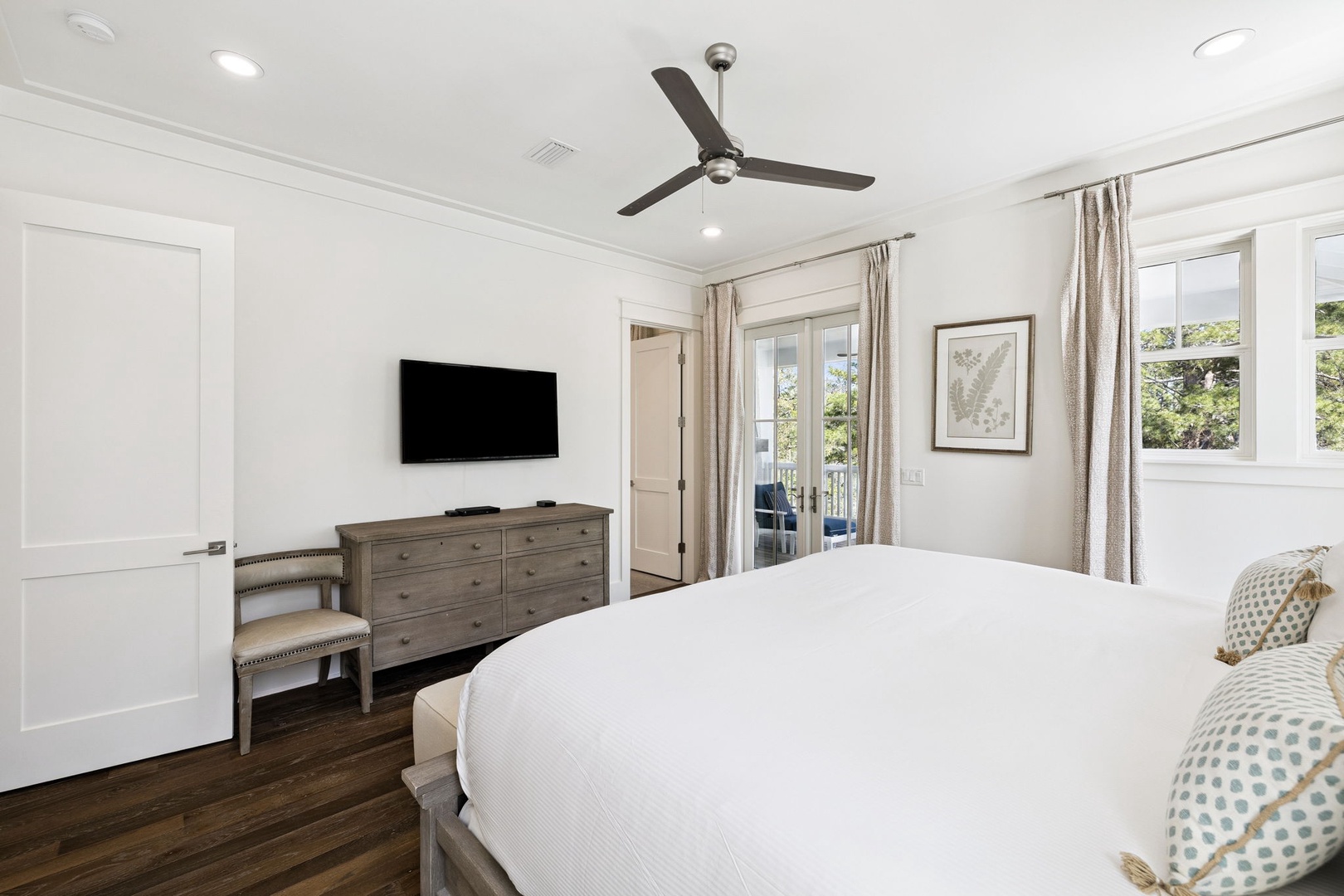 Sink into crisp white linens in your serene bedroom, where a ceiling fan keeps you cool and French doors invite natural light.