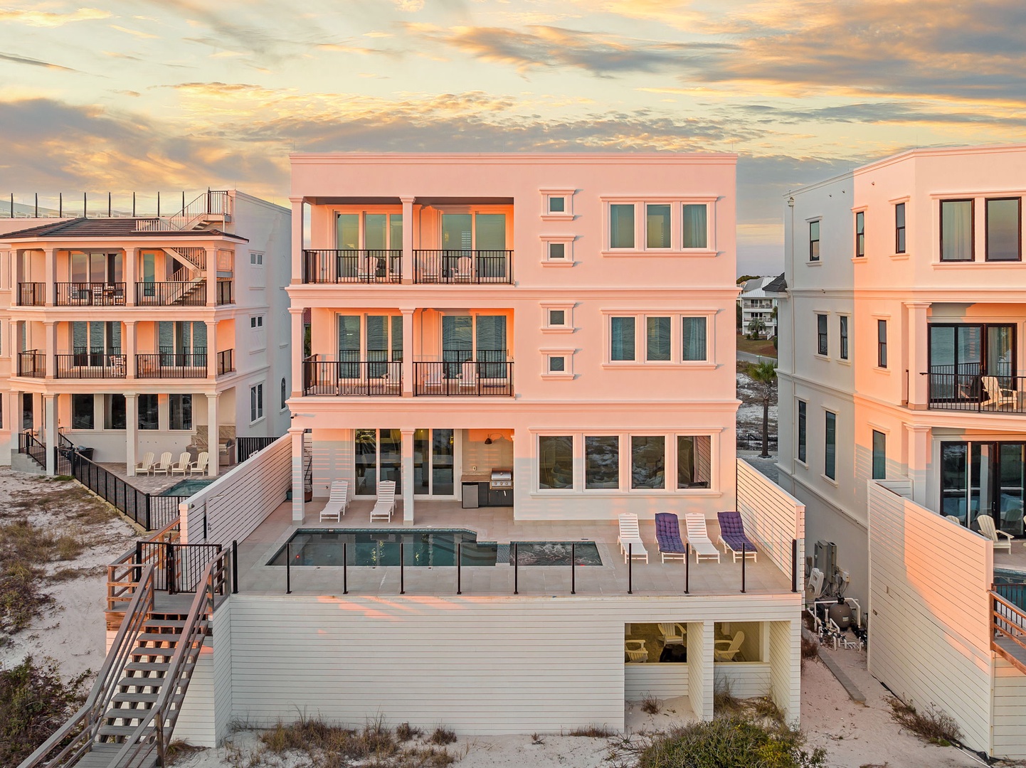 Stunning beachfront vacation rental with private pool and multiple balconies, perfectly positioned among coastal dunes at golden hour.