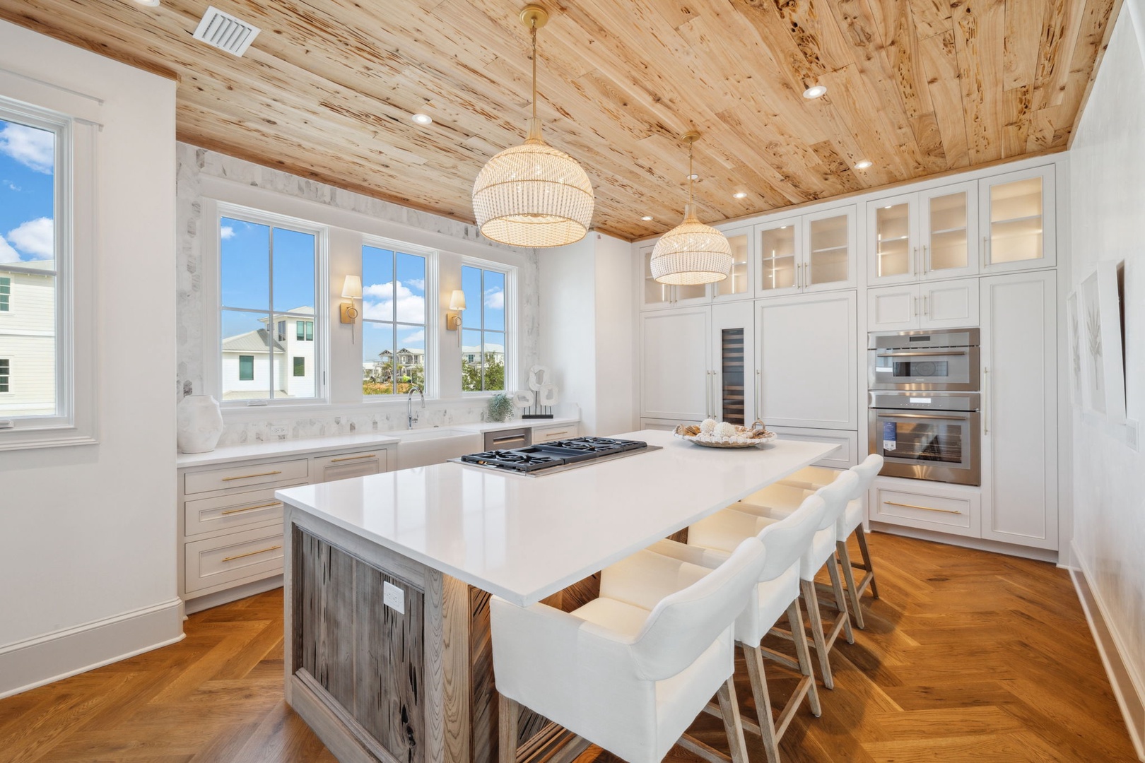 Gather in this chef-inspired kitchen where natural wood ceilings meet modern elegance. Prepare meals at the spacious island while loved ones keep you company in crisp coastal style.