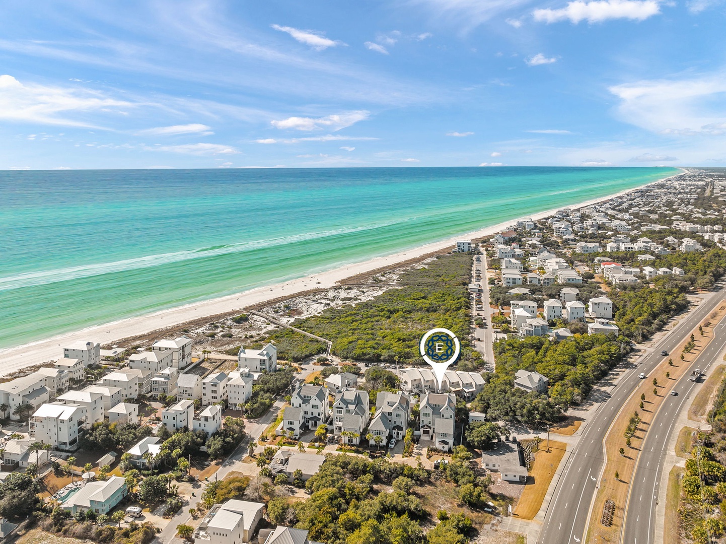 Aerial view of beachfront community with pristine turquoise waters and white sand beach stretching along the emerald coast.
