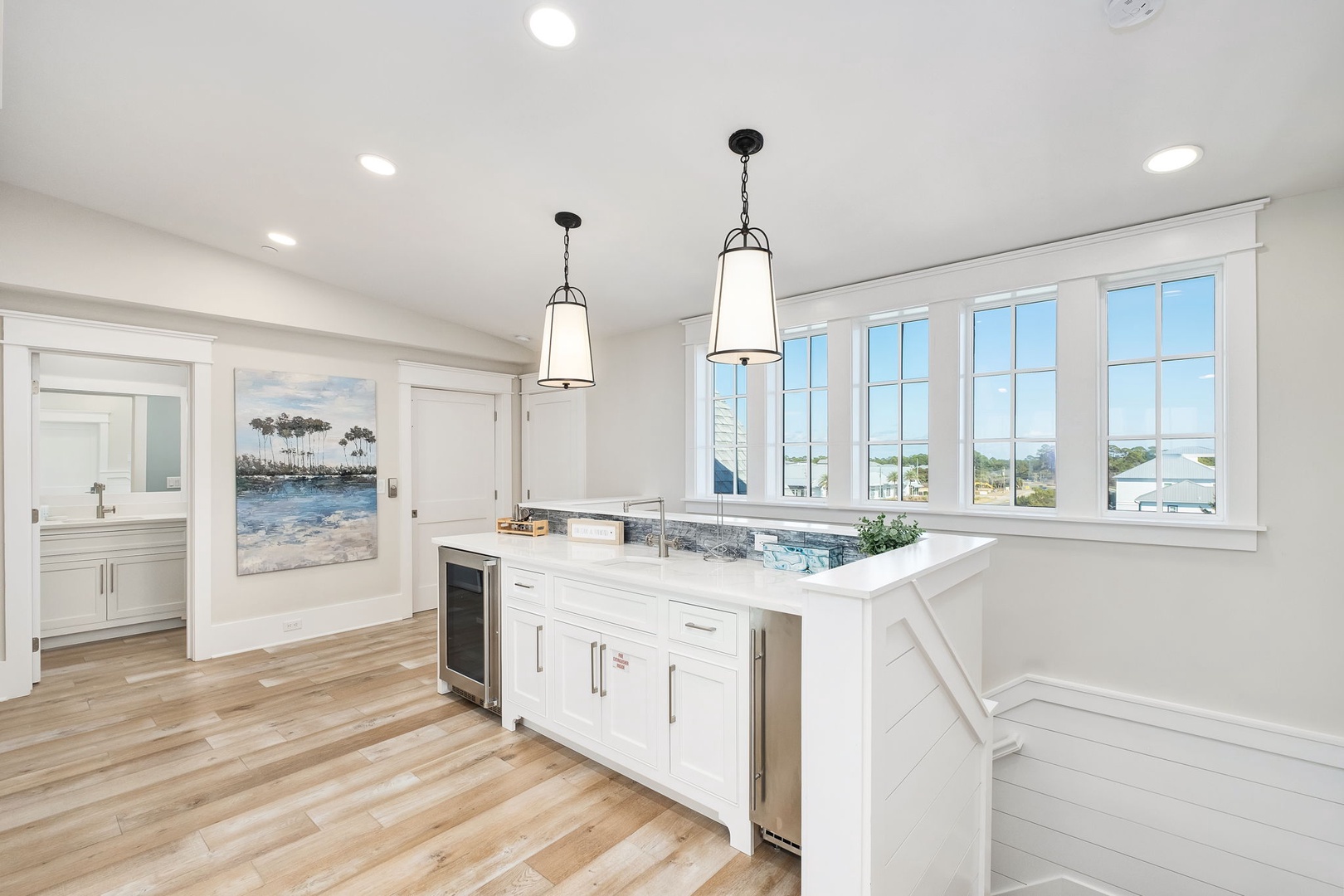 Your bright kitchen island becomes the heart of coastal living, with pendant lights and windows framing endless water views.