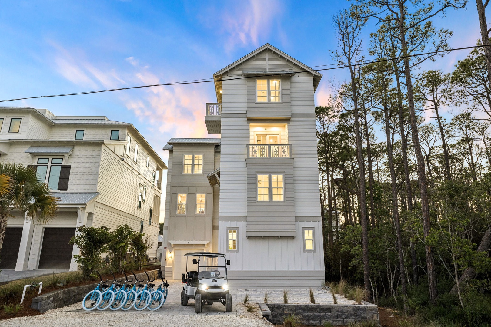 Modern coastal home with warm lighting amid natural surroundings, featuring convenient bike access and peaceful neighborhood setting.