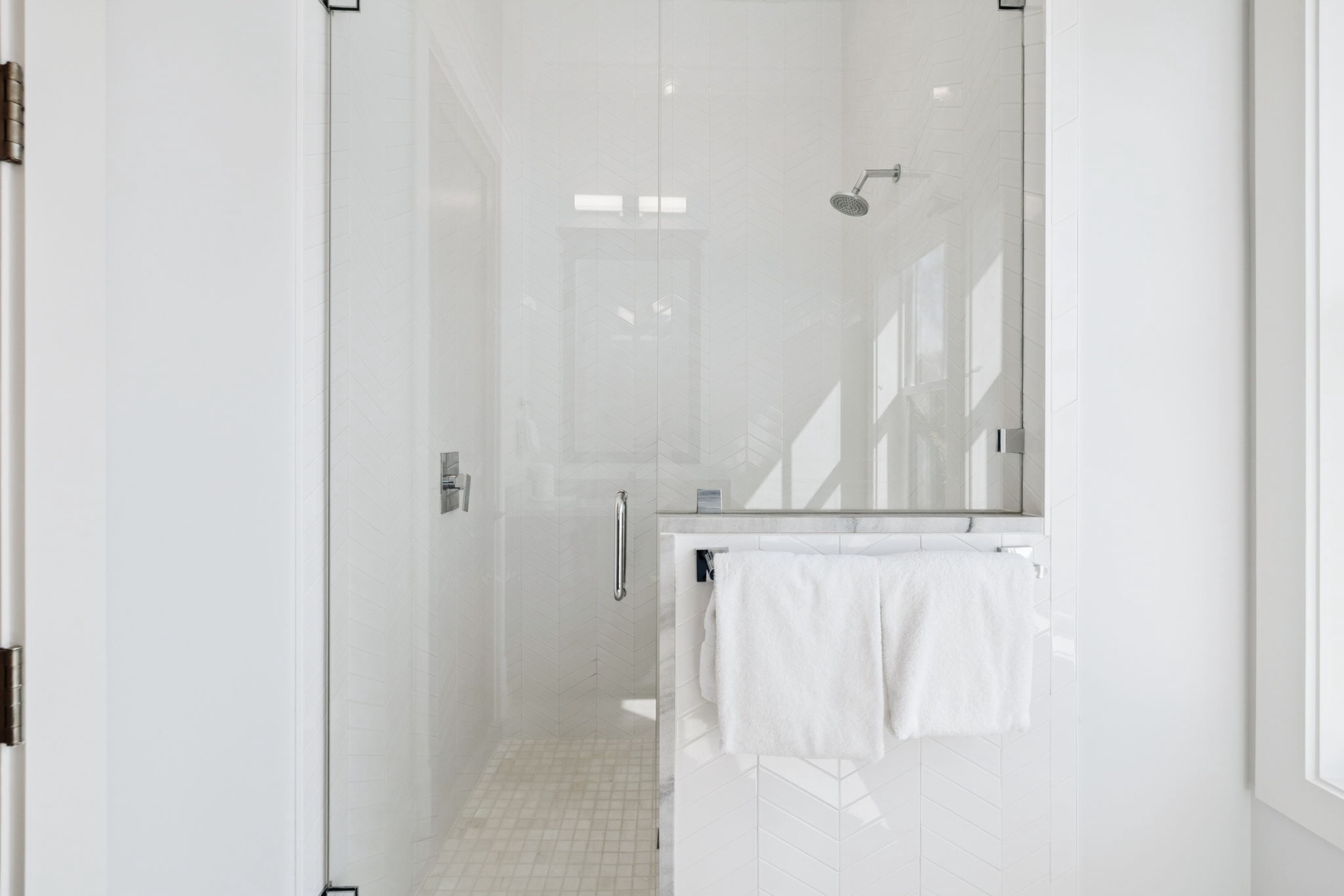 Step into your pristine glass-enclosed shower with luxurious marble details and fluffy towels waiting nearby.