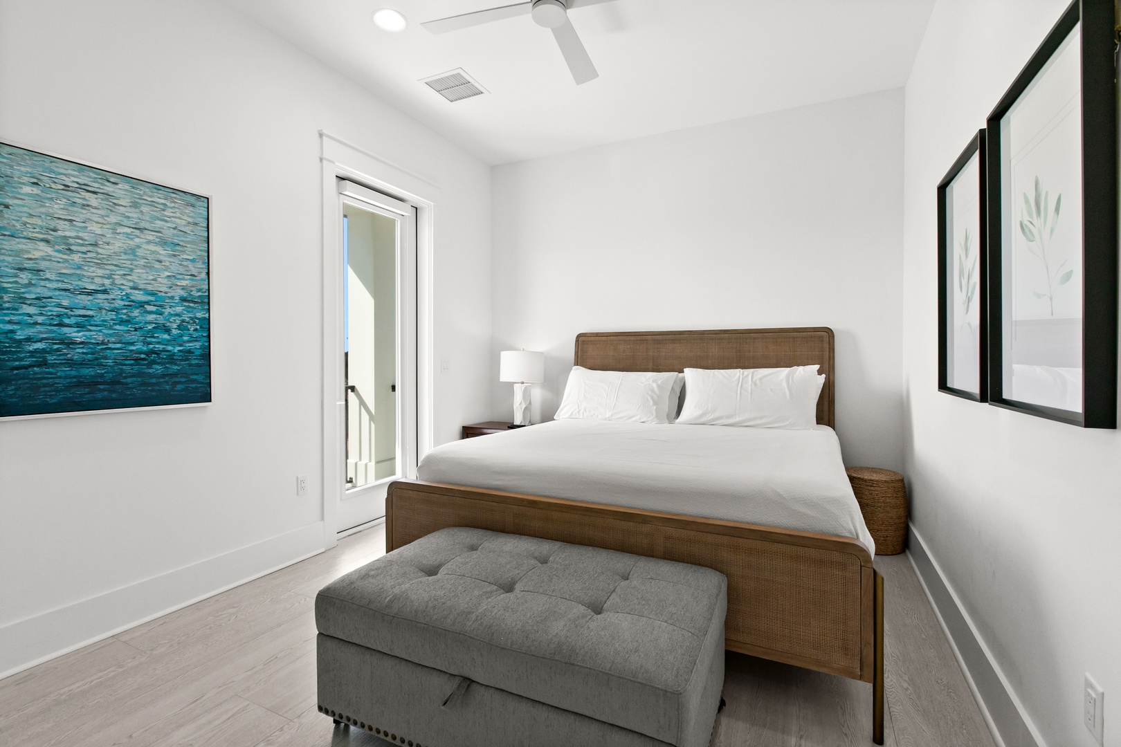 Sink into crisp white linens and let the ceiling fan's gentle breeze lull you into complete relaxation in your serene coastal-inspired bedroom.