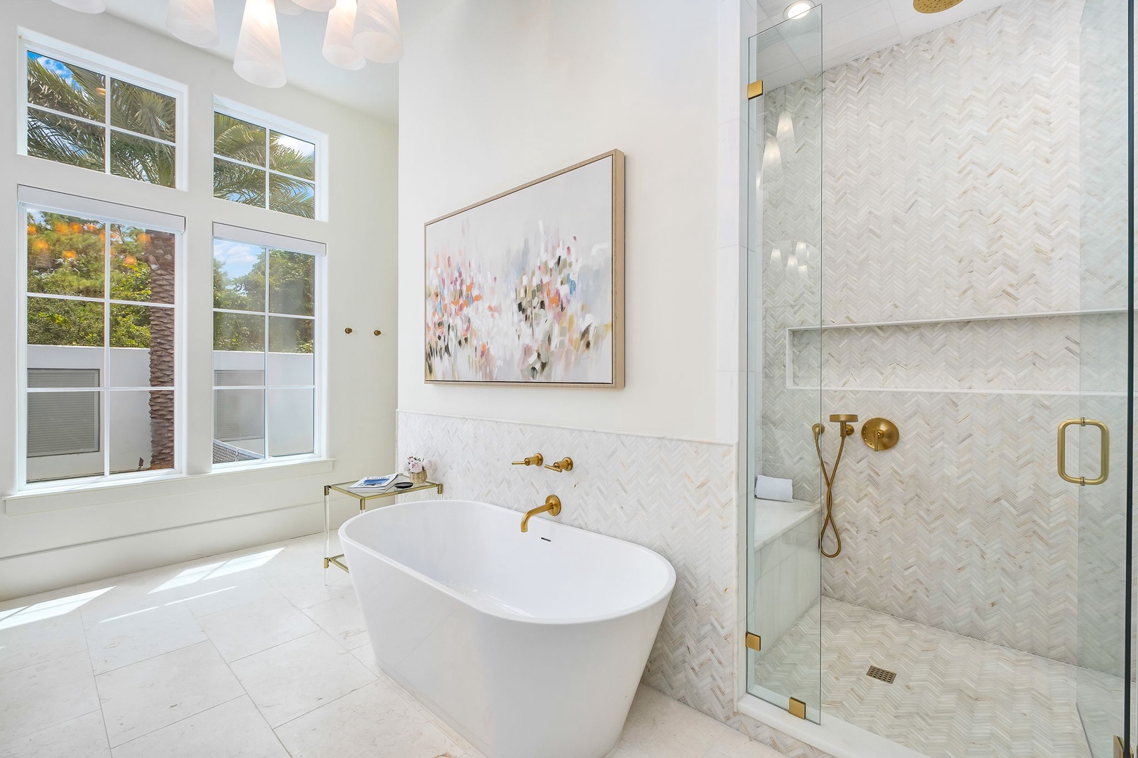 Slip into the freestanding tub for a long soak, or enjoy an invigorating rain shower behind glass. Elegant herringbone tile and warm brass fixtures create a serene, spa-like retreat.