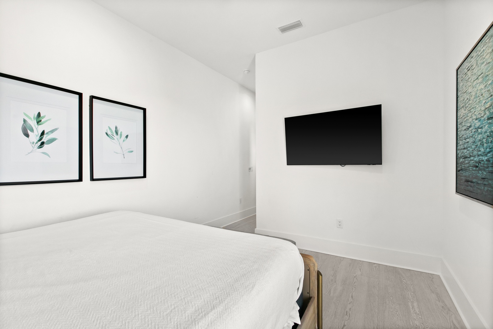 Unwind in your serene bedroom retreat, where crisp white walls and botanical artwork create a peaceful sanctuary. The plush bed invites restful nights, while modern amenities keep you comfortable throughout your stay.