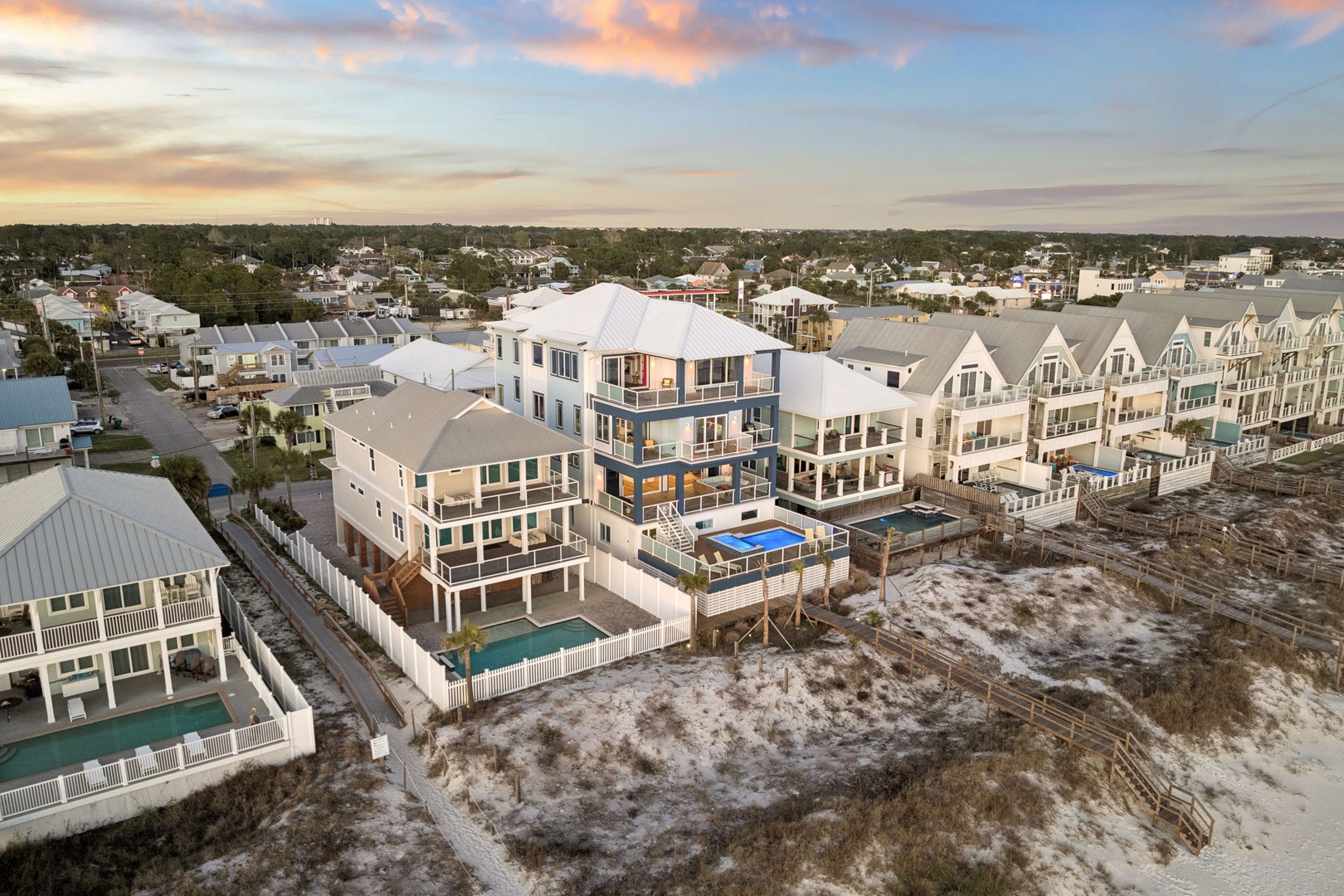 Stunning beachfront community captured at golden hour, showcasing modern coastal architecture with private pools and direct beach access along pristine sandy shores.