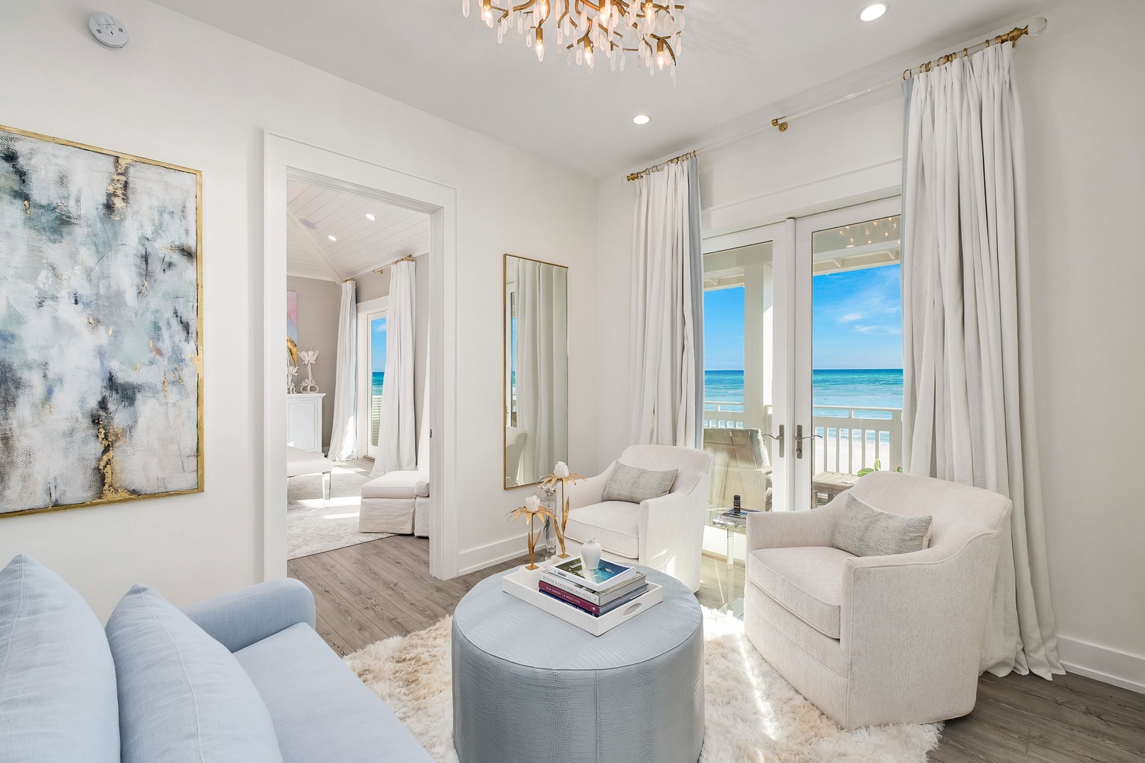 Sink into plush seating as sunlight and ocean breezes fill your elegant living space, where coastal luxury meets comfort through floor-to-ceiling windows framing endless sea views.