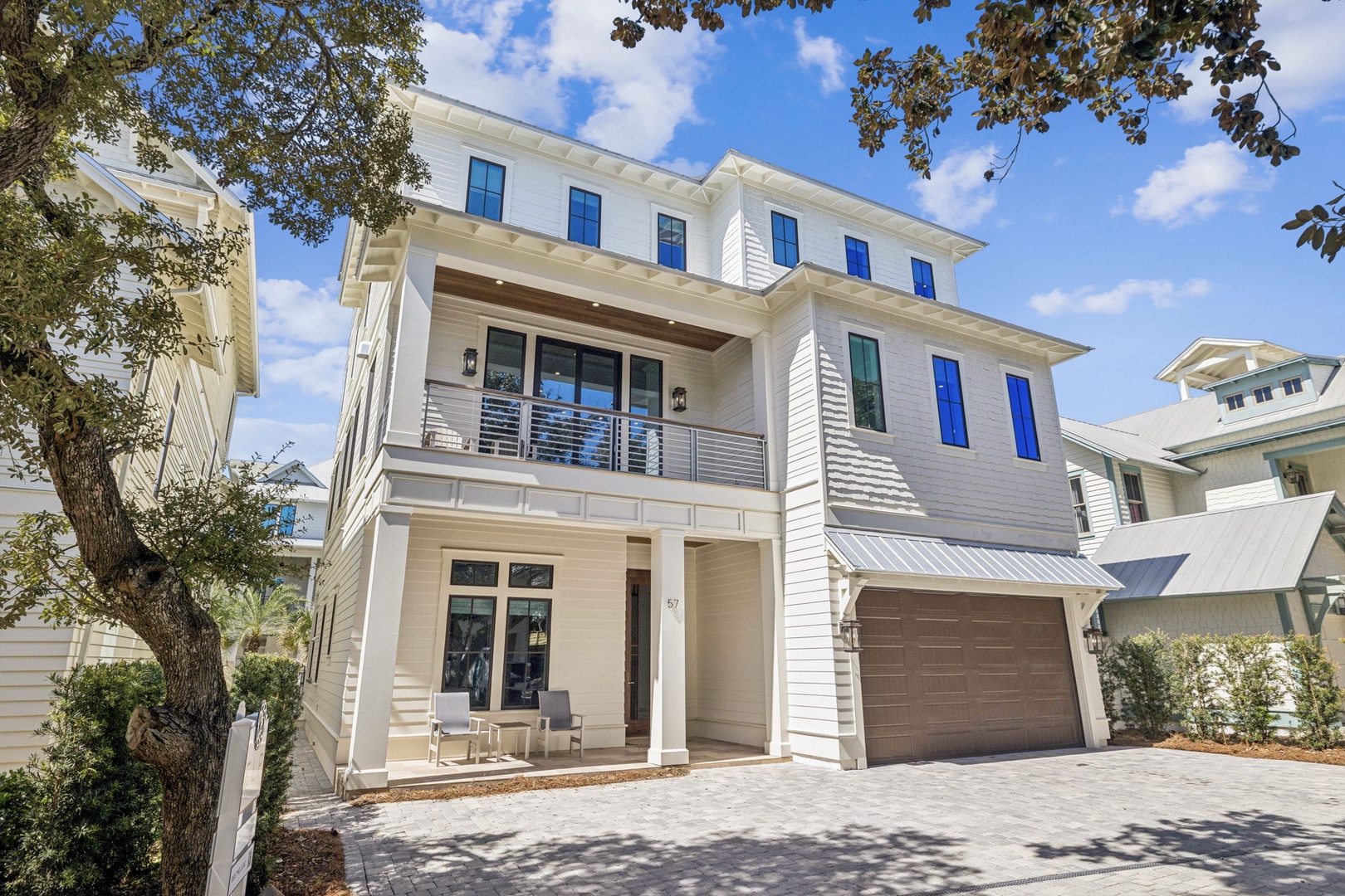 Beautiful modern coastal home with elegant white architecture, featuring spacious balconies and a private driveway in a tranquil neighborhood setting.