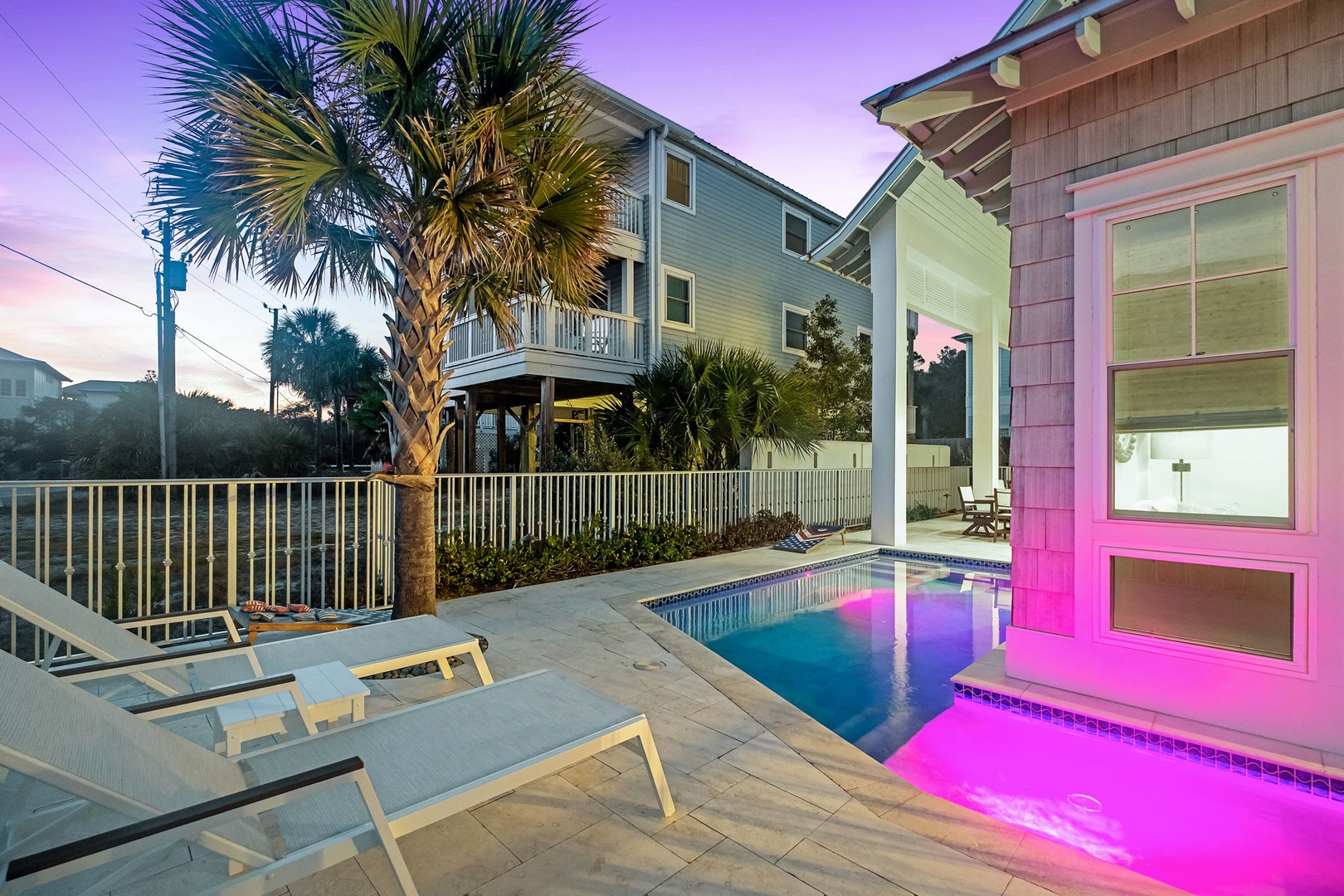 Stunning beach house with private pool featuring colorful LED lighting and tropical palm trees, perfect for evening relaxation.