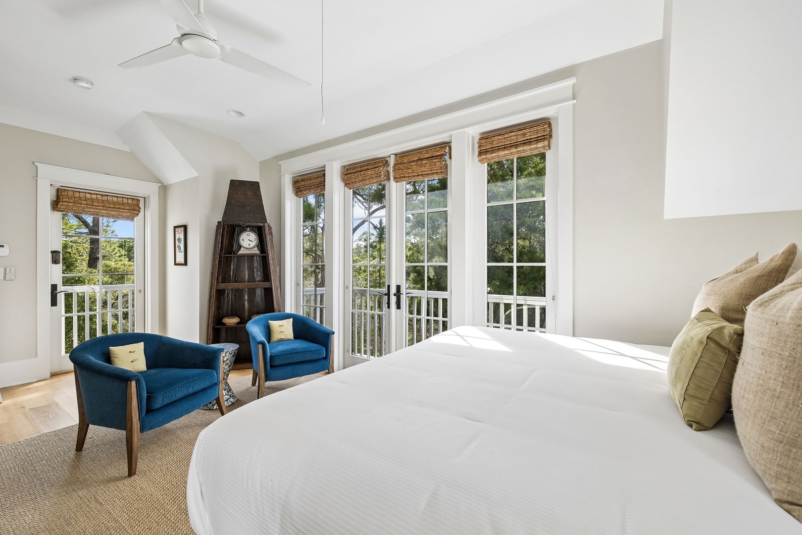 Drift off in your airy bedroom where tall ceilings and French doors frame lush greenery beyond the private balcony, blending comfort with calming coastal vibes.