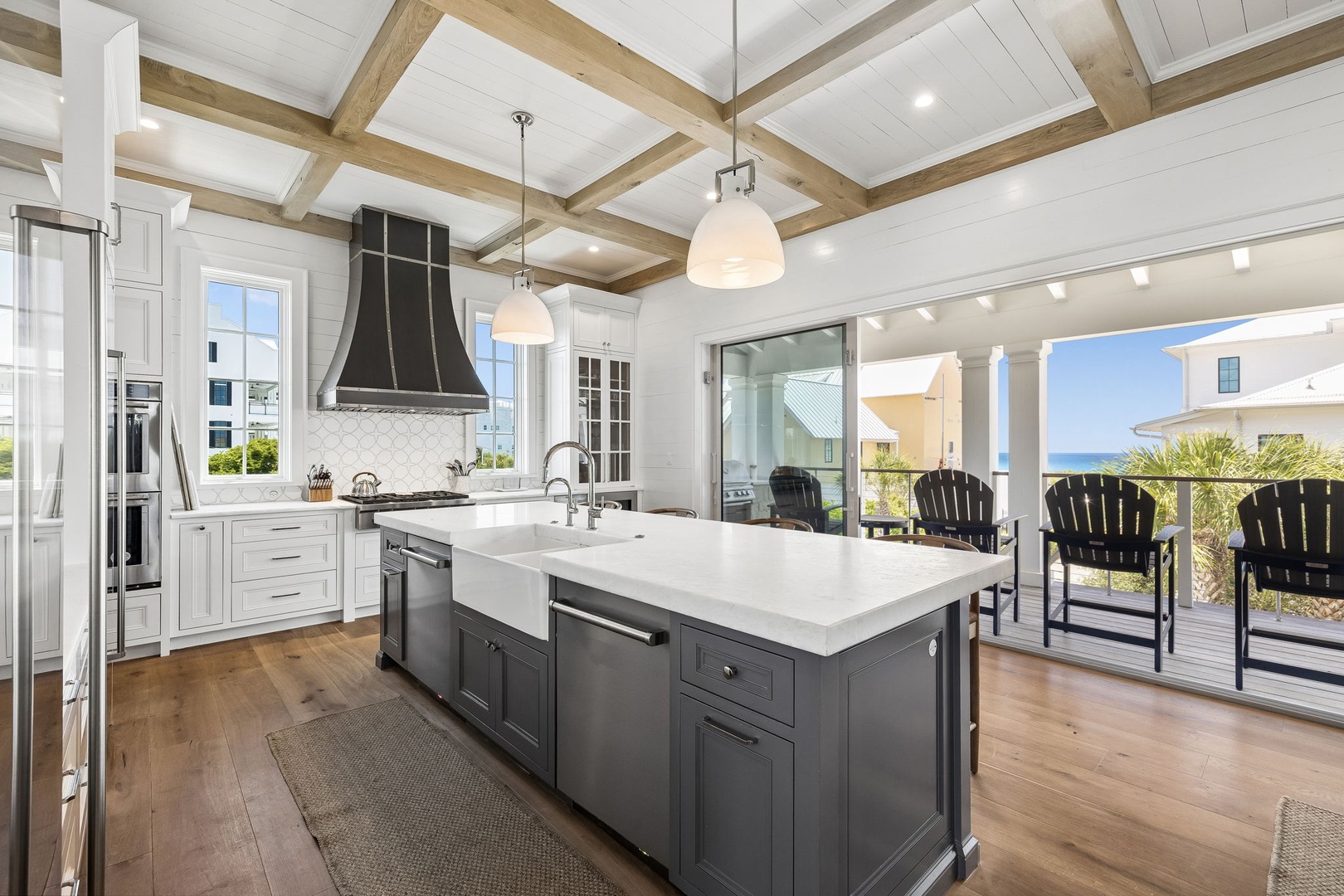 Gather around the spacious island and imagine preparing memorable meals in this elegant kitchen with soaring beamed ceilings, bright natural light, and sweeping ocean views just beyond your private deck.