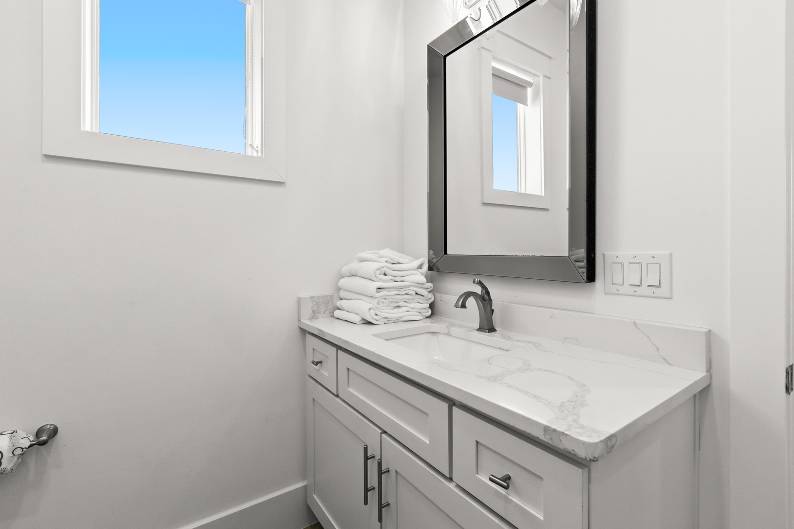 Your bathroom features crisp white marble counters and soft, plush towels waiting for you after a refreshing shower.