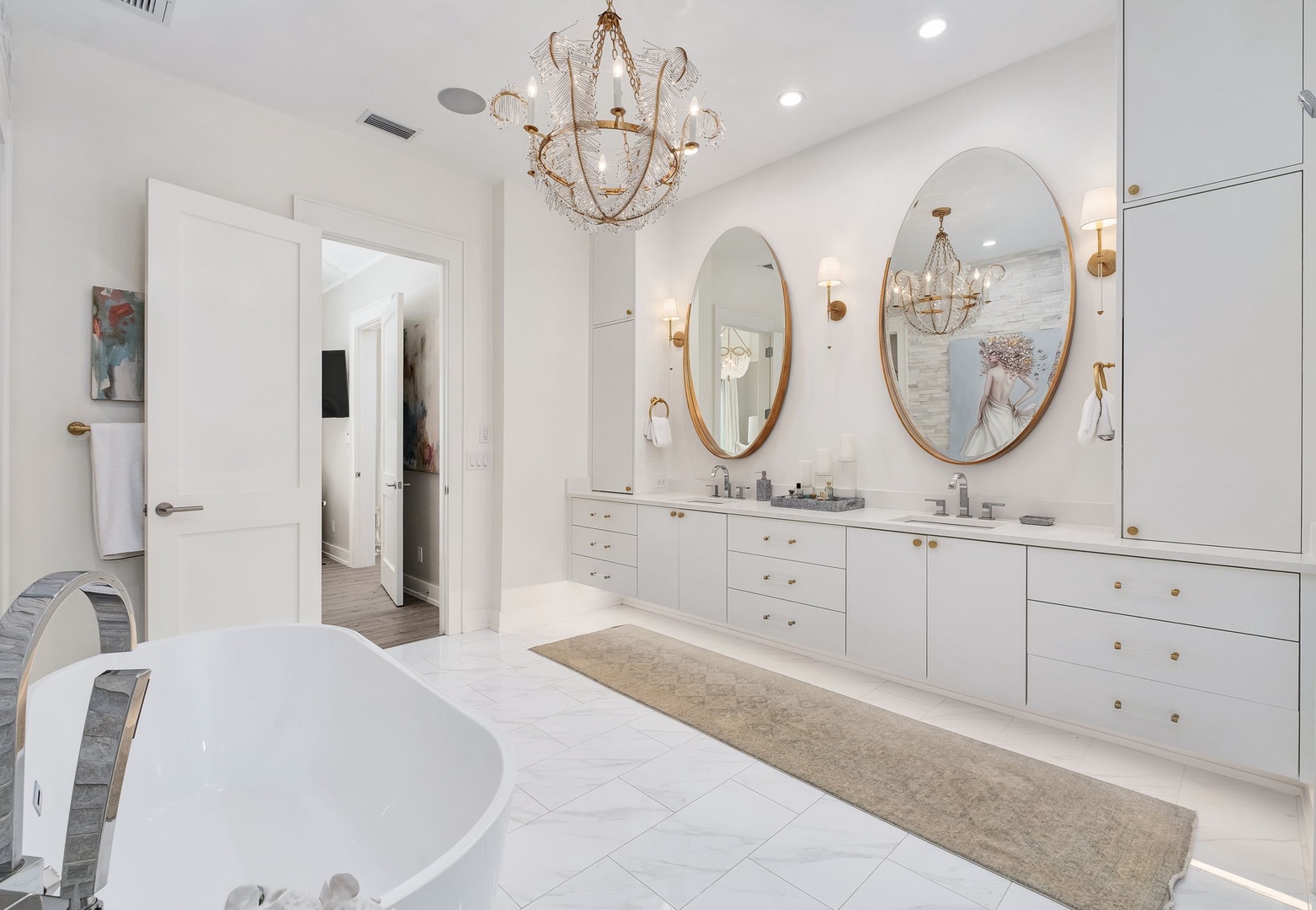 Unwind in your private spa-like bathroom, where elegant gold-framed mirrors and a stunning chandelier create a luxurious retreat after a day of exploring.