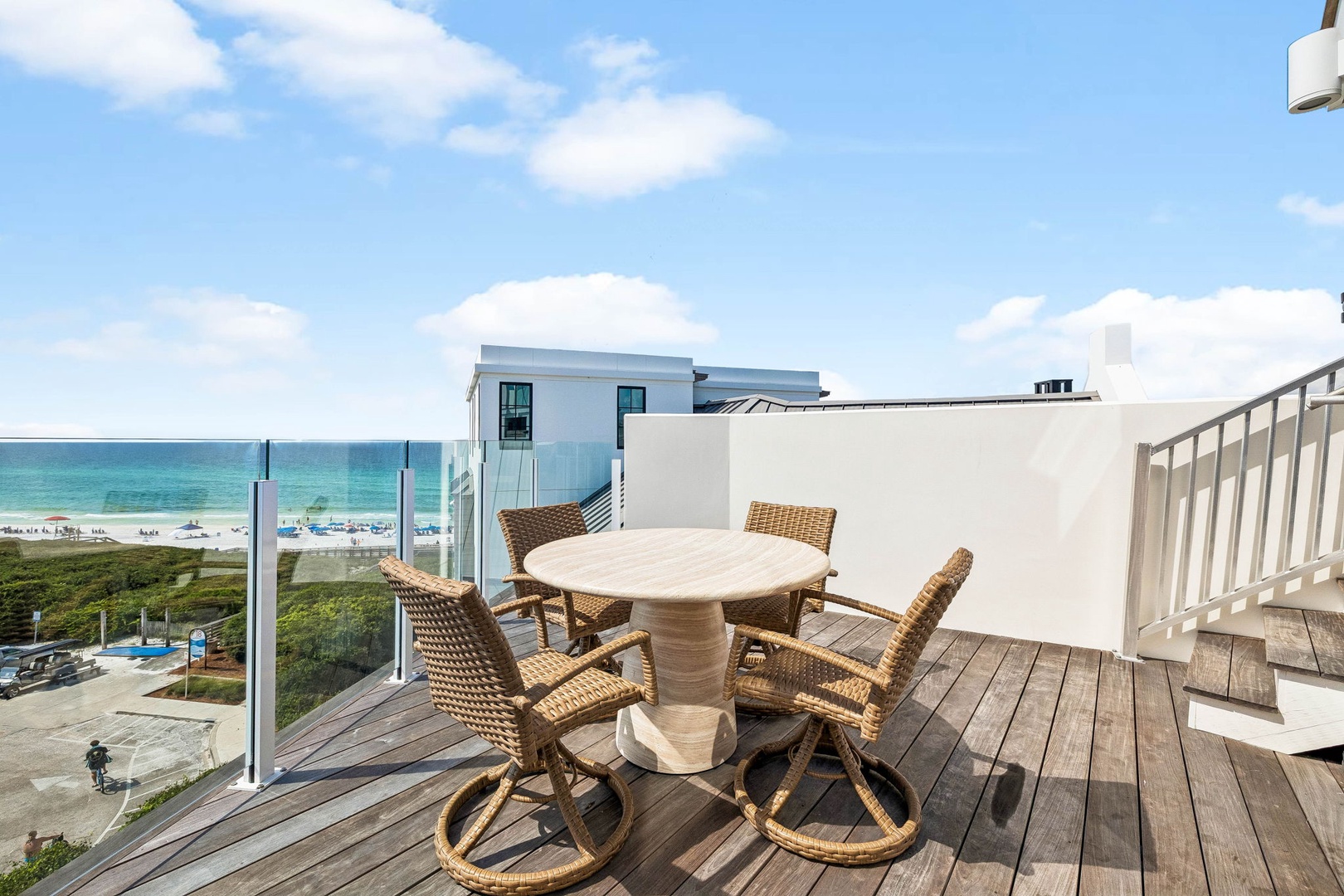 A private balcony with wicker dining chairs and stunning ocean views, positioned steps from the sandy beach below.