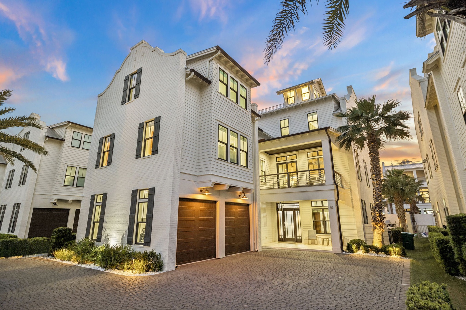 Modern coastal homes featuring elegant architecture and tropical landscaping create an upscale neighborhood atmosphere as evening approaches.
