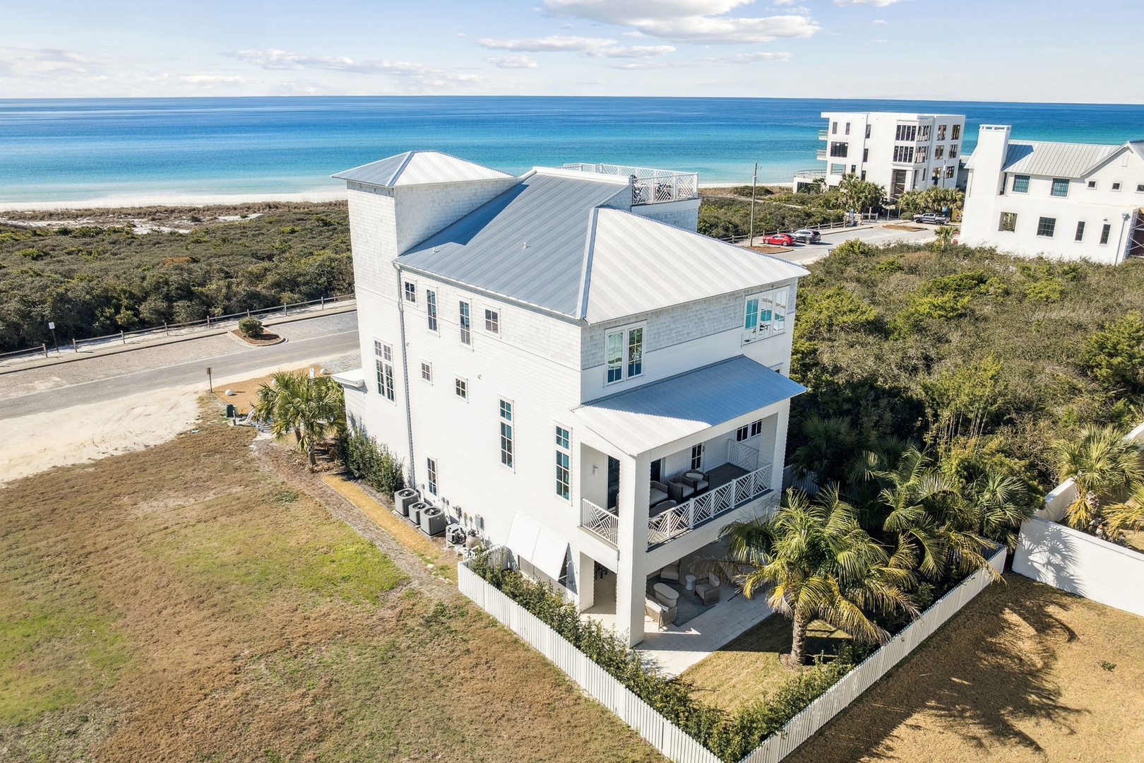 Stunning beachfront property featuring a modern coastal home with metal roofing, surrounded by tropical landscaping and just steps from pristine sandy beaches.
