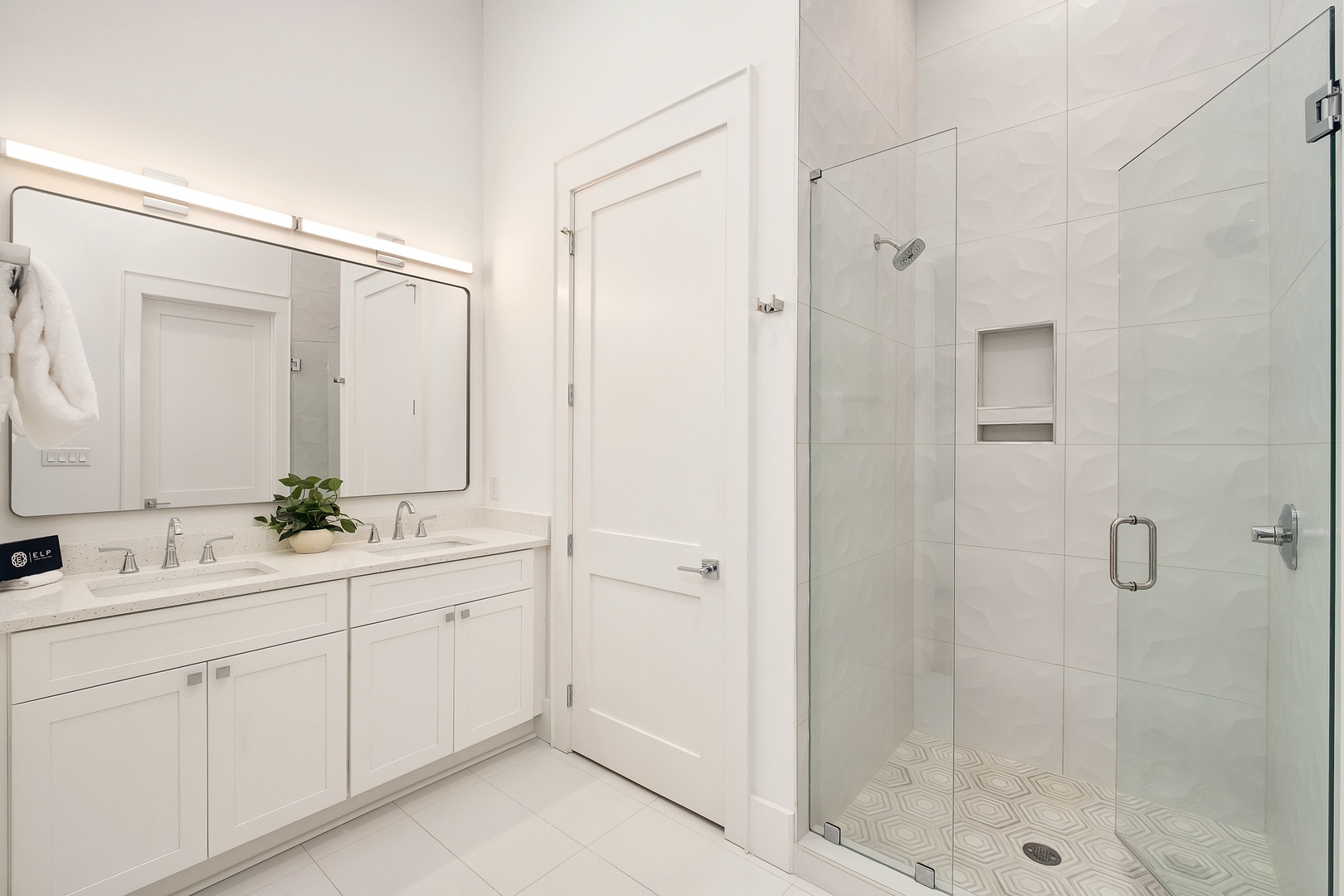 Step into your pristine white bathroom with dual vanities, marble countertops, and a spacious glass-enclosed shower for luxurious daily routines.