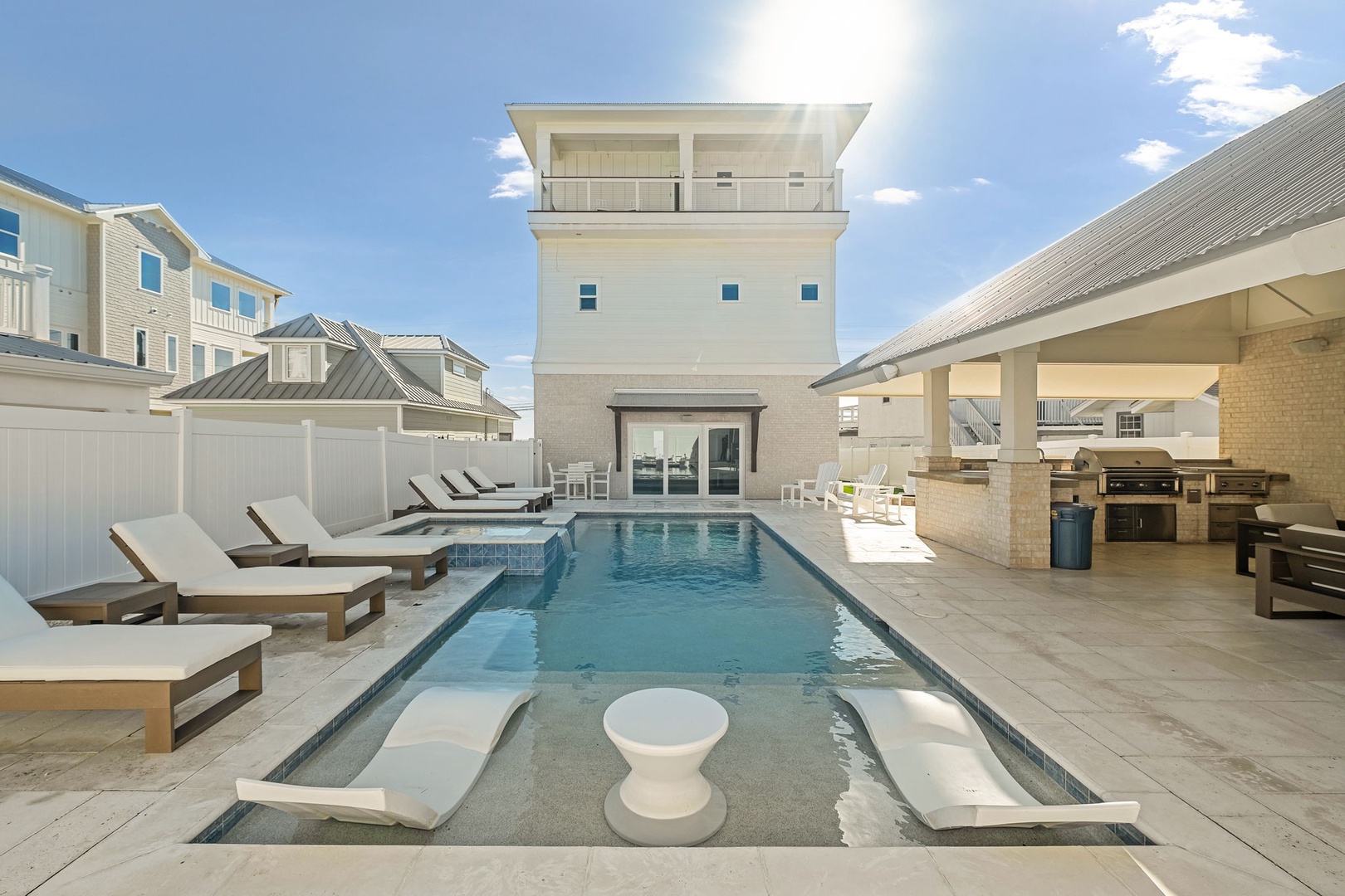 Dive into your private oasis featuring a stunning pool with built-in loungers, spacious deck, and covered outdoor kitchen for perfect entertaining.