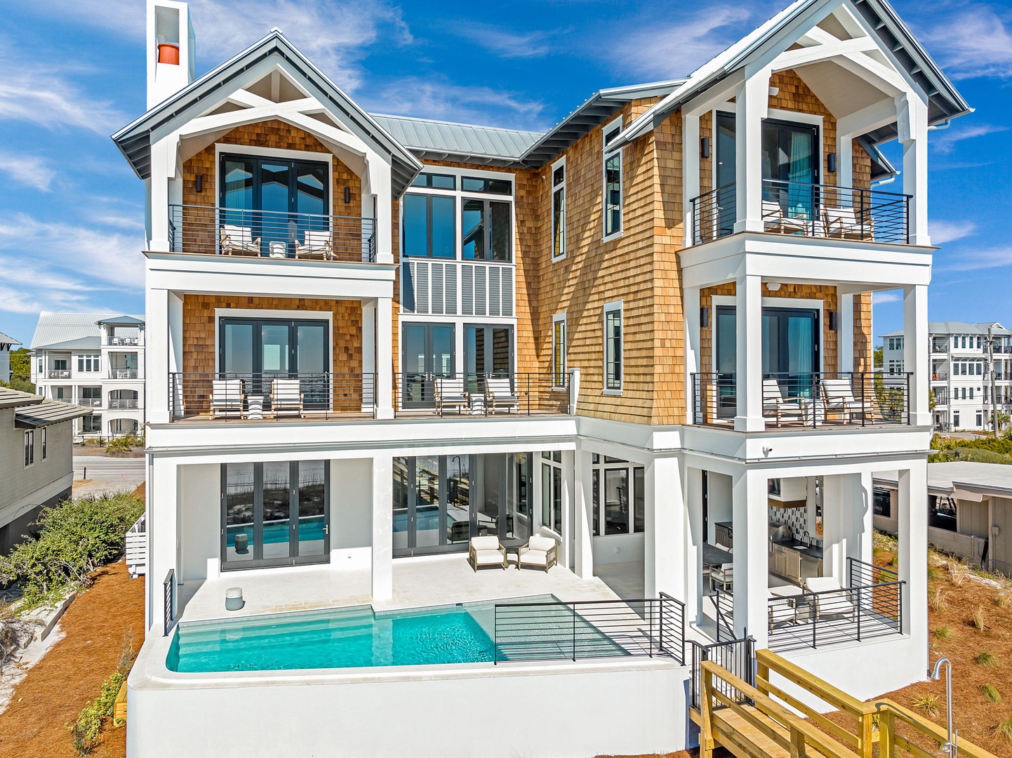 Modern coastal architecture featuring natural cedar shingles, multiple balconies, and a private pool in an upscale beachside neighborhood.