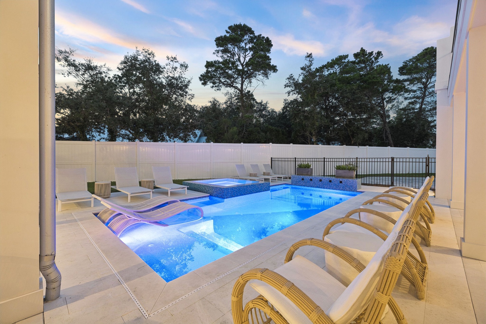 Your private pool oasis awaits as day turns to dusk, complete with built-in loungers, a bubbling spa, and plenty of sunbathing space surrounded by peaceful trees.