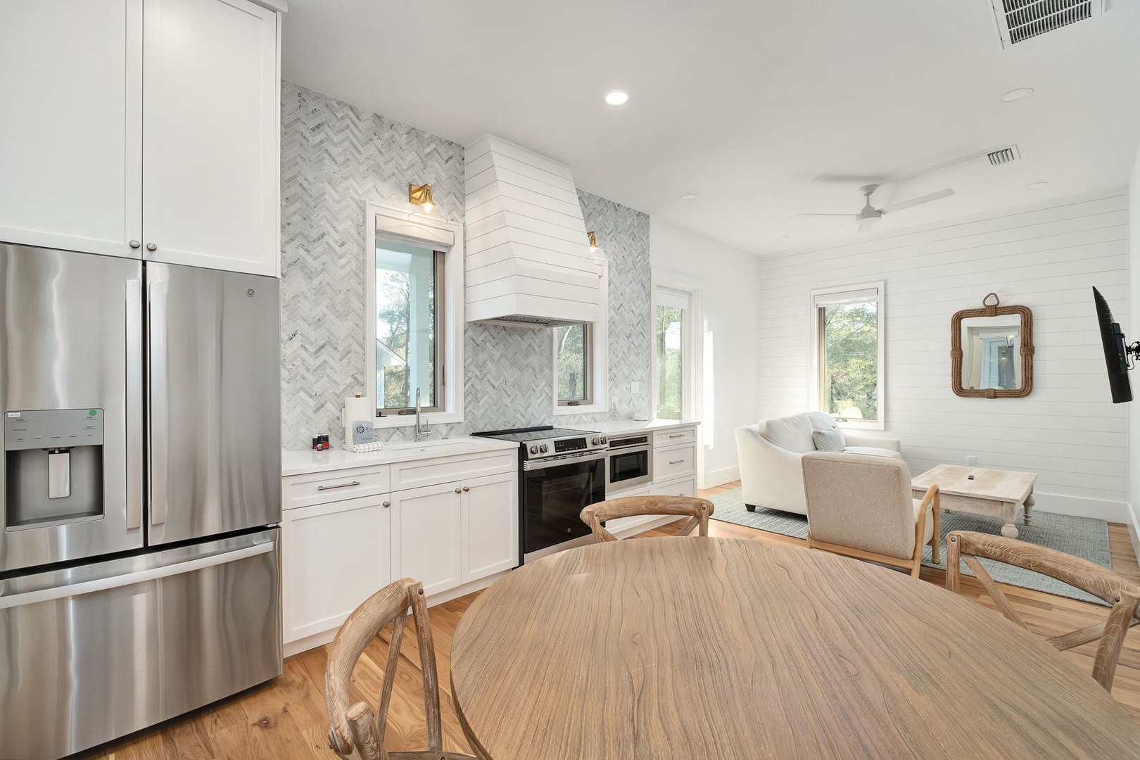Your bright open kitchen flows seamlessly into the living area, featuring marble herringbone backsplash and modern stainless appliances for memorable meals.