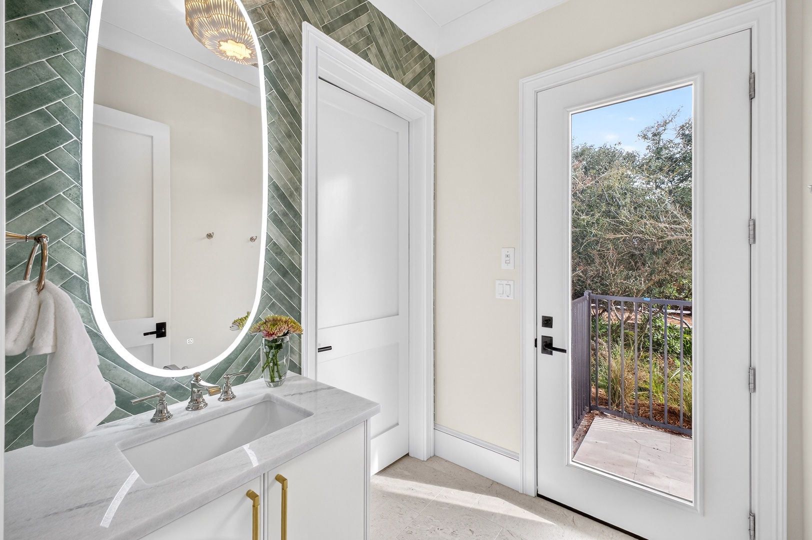 Freshen up in your stylish bathroom featuring elegant green herringbone tiles and a sleek vanity, with private balcony access.