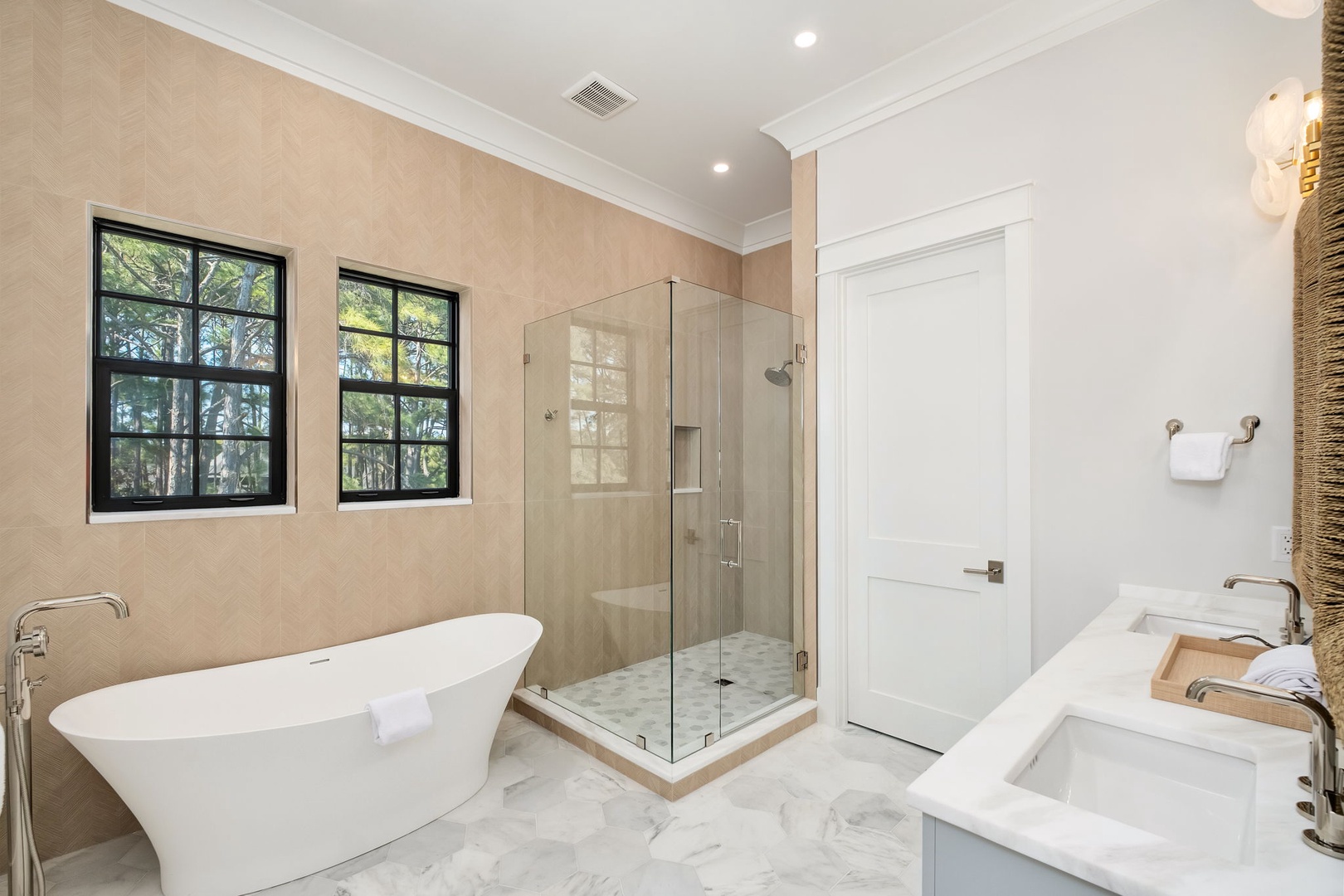 Unwind in your luxurious spa-like bathroom featuring a soaking tub, marble floors, and glass shower enclosure bathed in natural light.