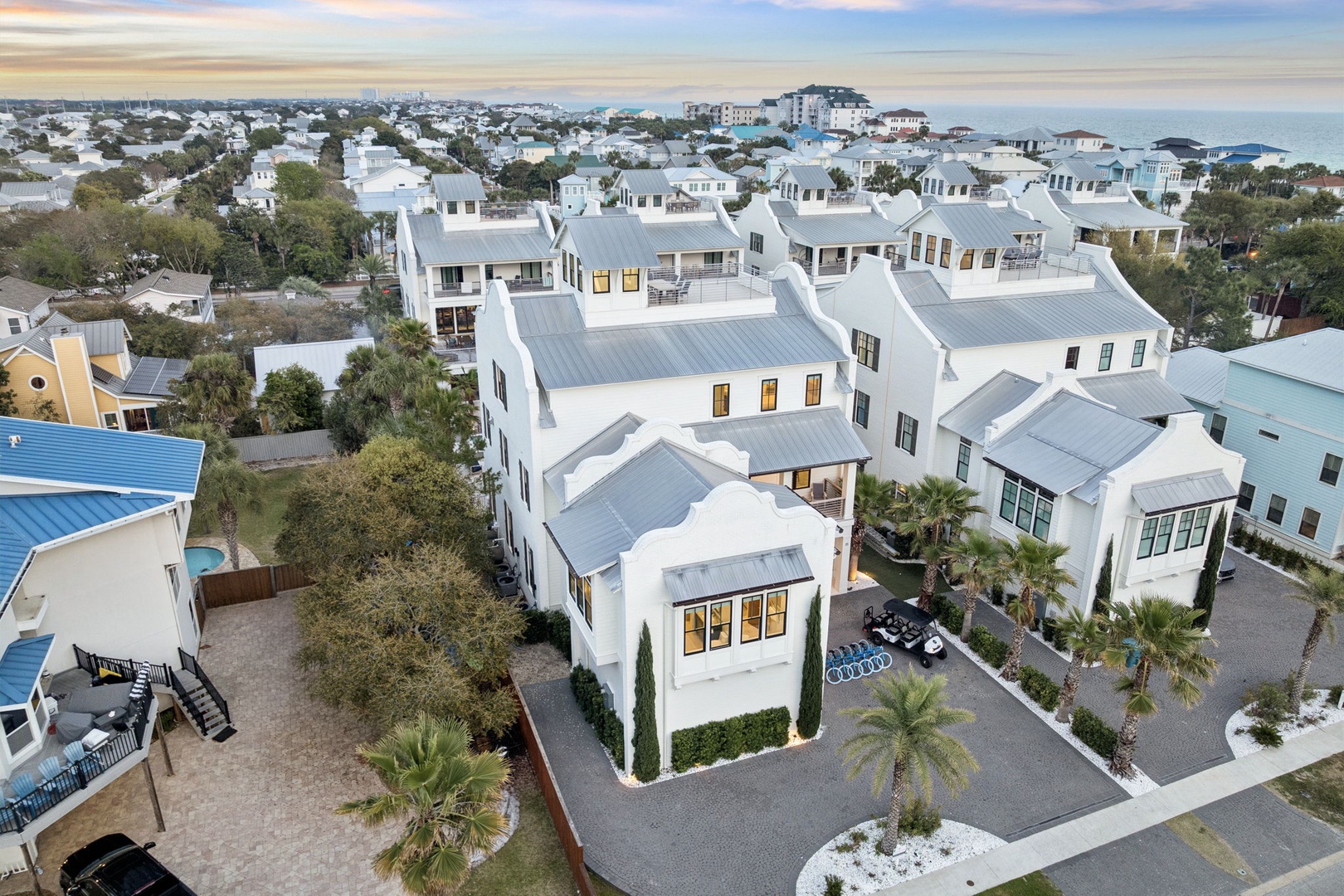 Aerial view of coastal vacation rental community featuring modern homes with metal roofing in a charming seaside neighborhood.