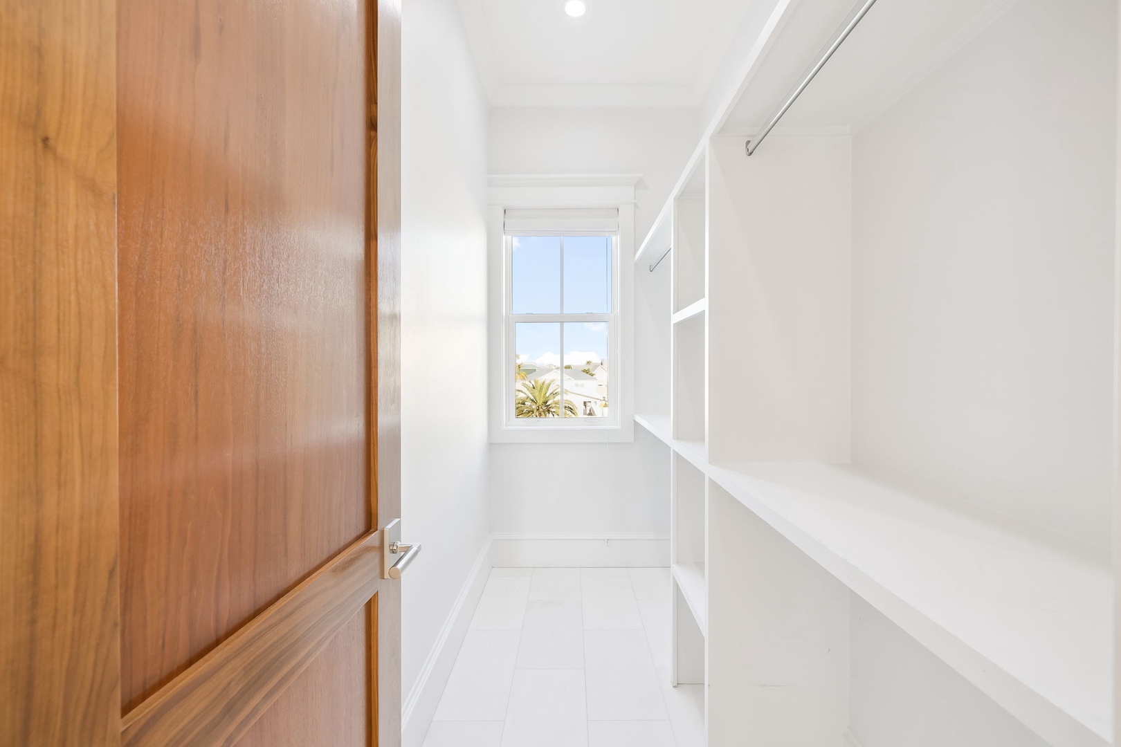 Your walk-in closet offers pristine white shelving and warm wood finishes, with natural light streaming through windows.