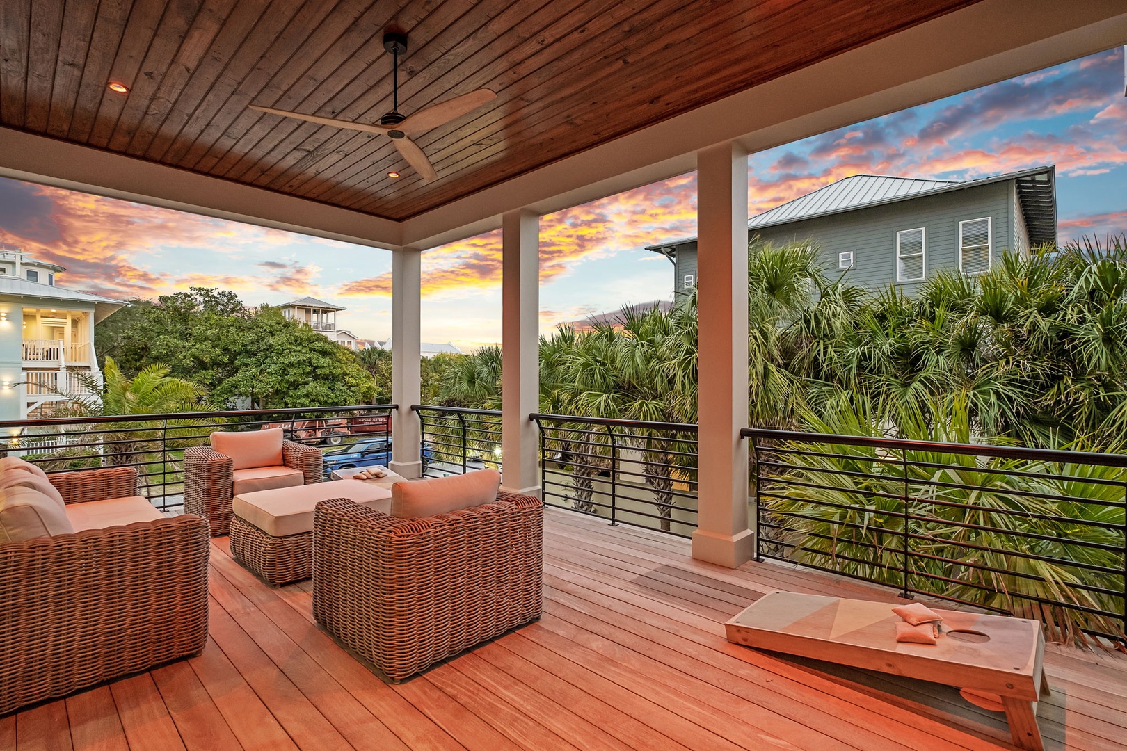 Unwind in your private covered terrace with plush wicker seating, ceiling fan comfort, and stunning sunset views through tropical palms.