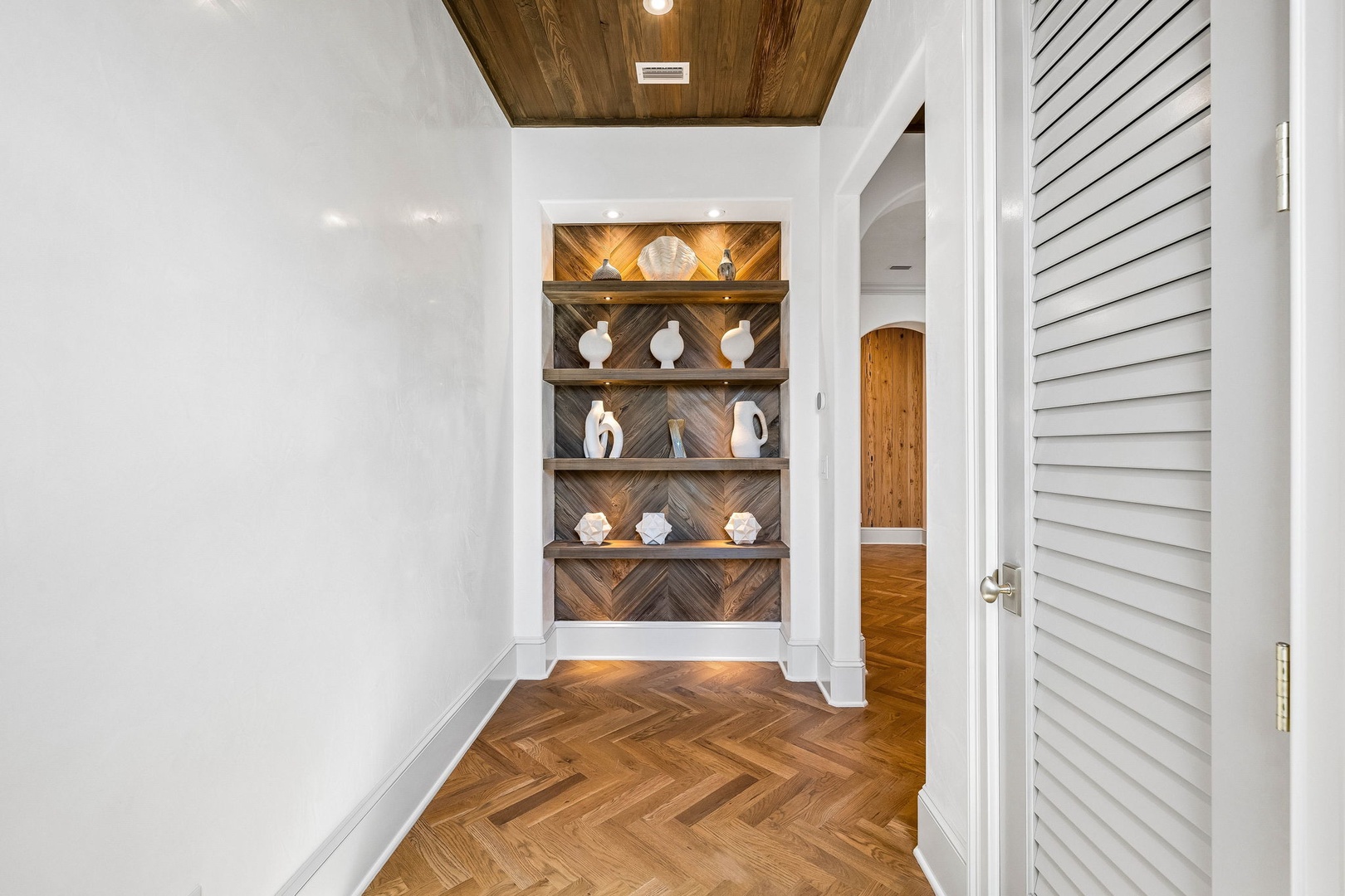 Step into a space where artisan details meet modern comfort—stunning herringbone floors, rich wood ceiling, and custom shelving with coastal accents create a welcoming retreat.