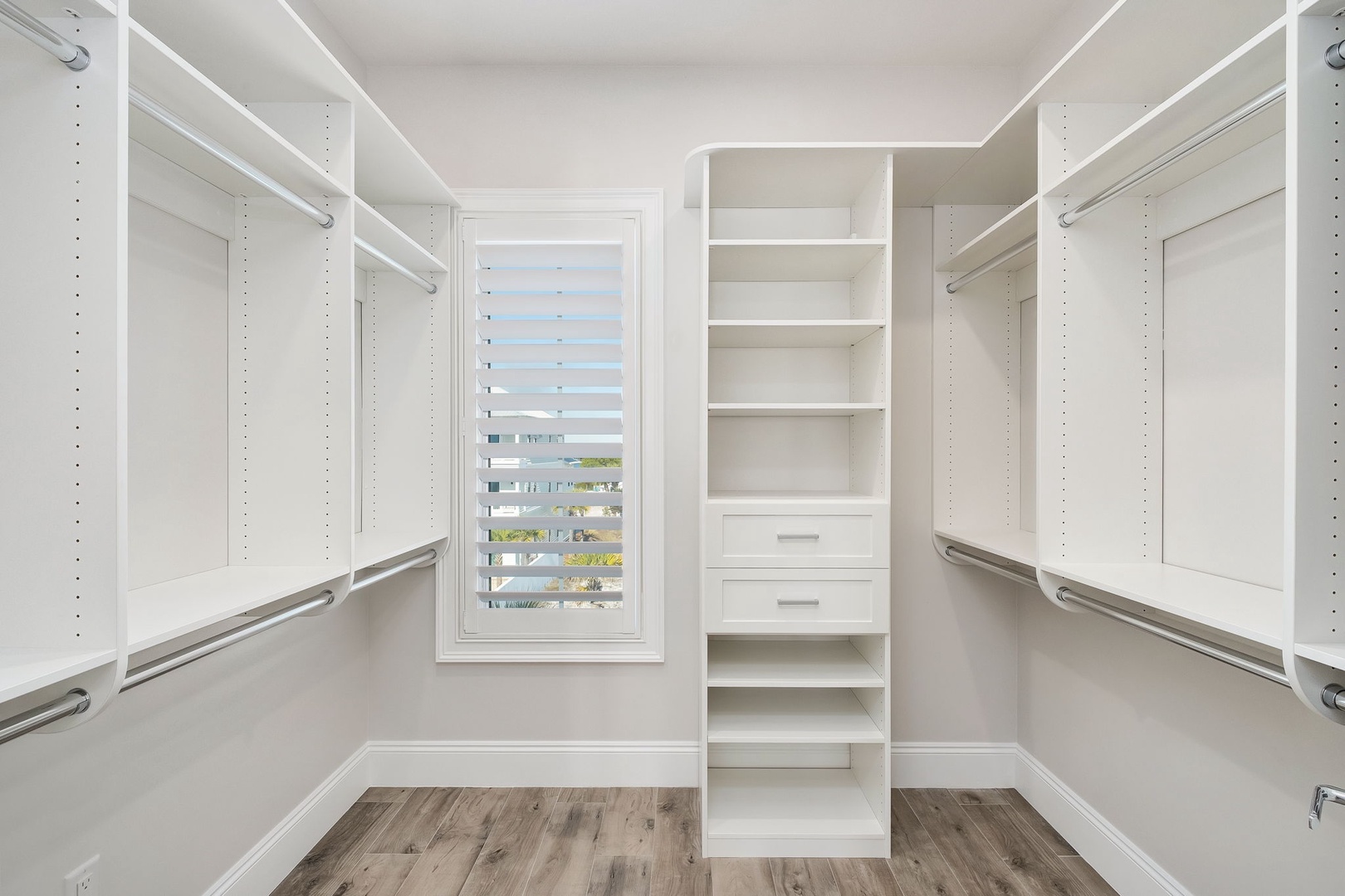 Your spacious walk-in closet features custom white built-ins with adjustable shelving, drawers, and hanging rods for all your wardrobe needs.