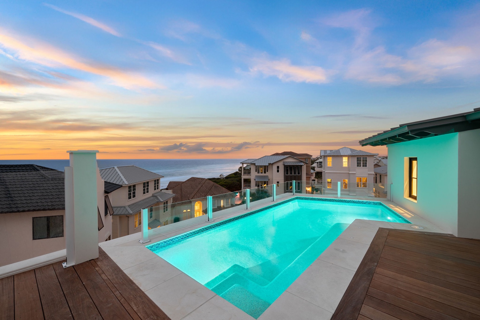 A stunning rooftop pool overlooks coastal sunsets and neighboring beach homes, providing a serene retreat in a prime location near the ocean.