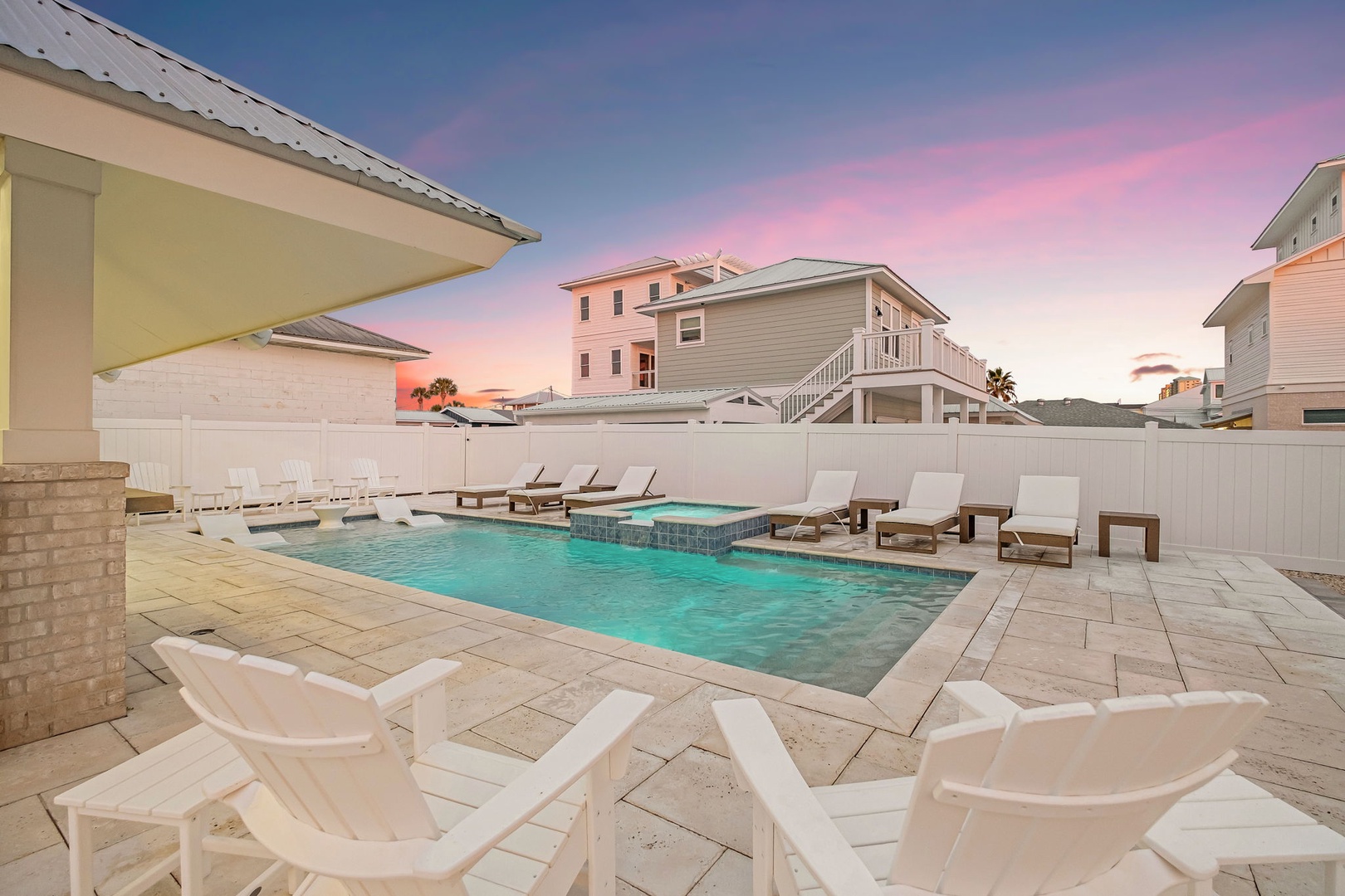 Stunning sunset paints the sky in pink and blue hues above this pristine pool area surrounded by coastal vacation homes.