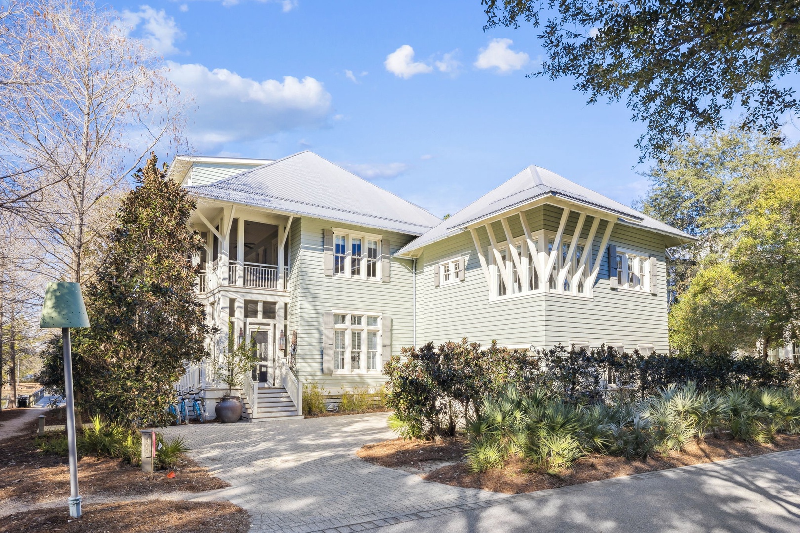 Beautiful two-story coastal home with wraparound porches and mature landscaping creates an inviting arrival experience.