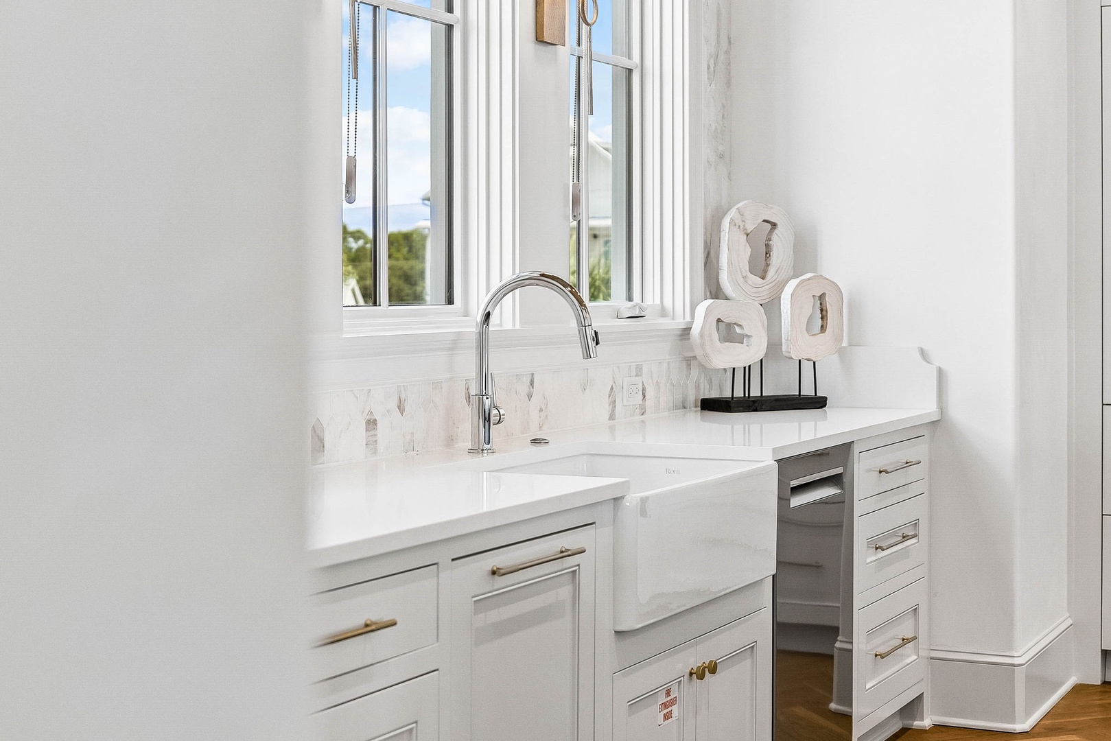 Crisp white cabinetry and marble-inspired countertops create your bright, airy kitchen workspace. Natural light pours through windows overlooking the lush greenery outside.