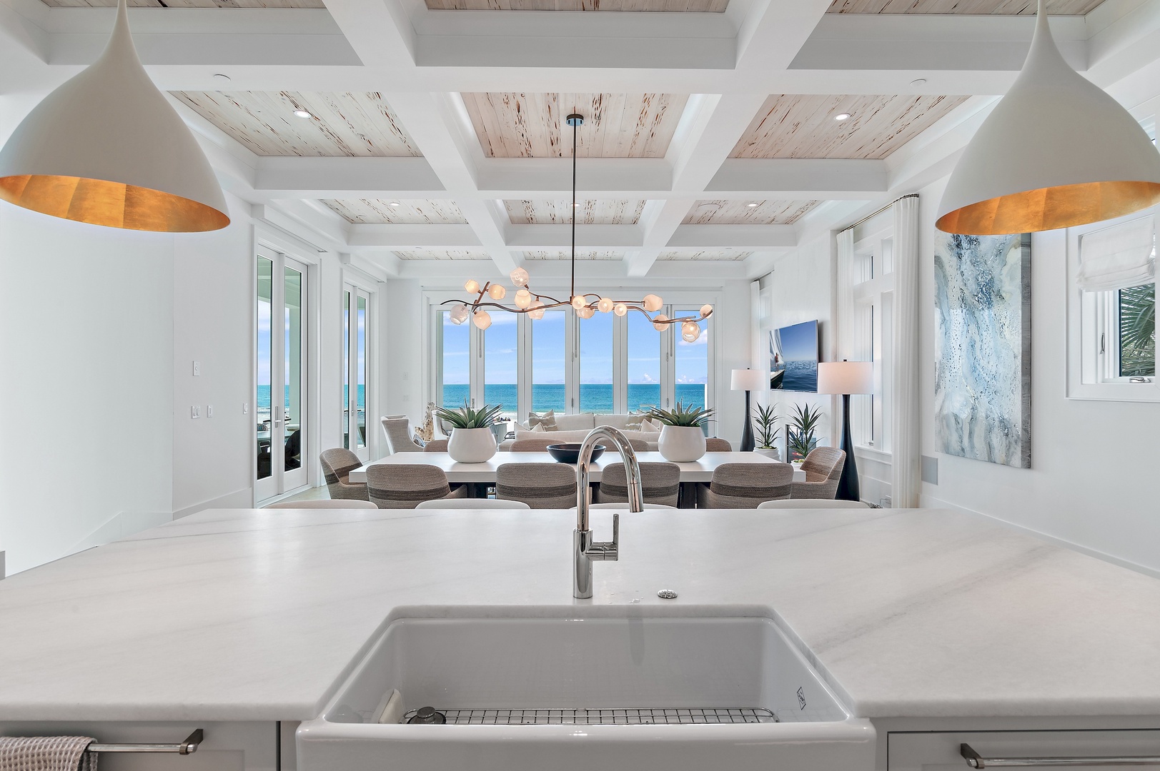 Your gourmet kitchen opens to breathtaking turquoise waters through floor-to-ceiling windows, blending coastal luxury with everyday comfort in this sun-drenched space.